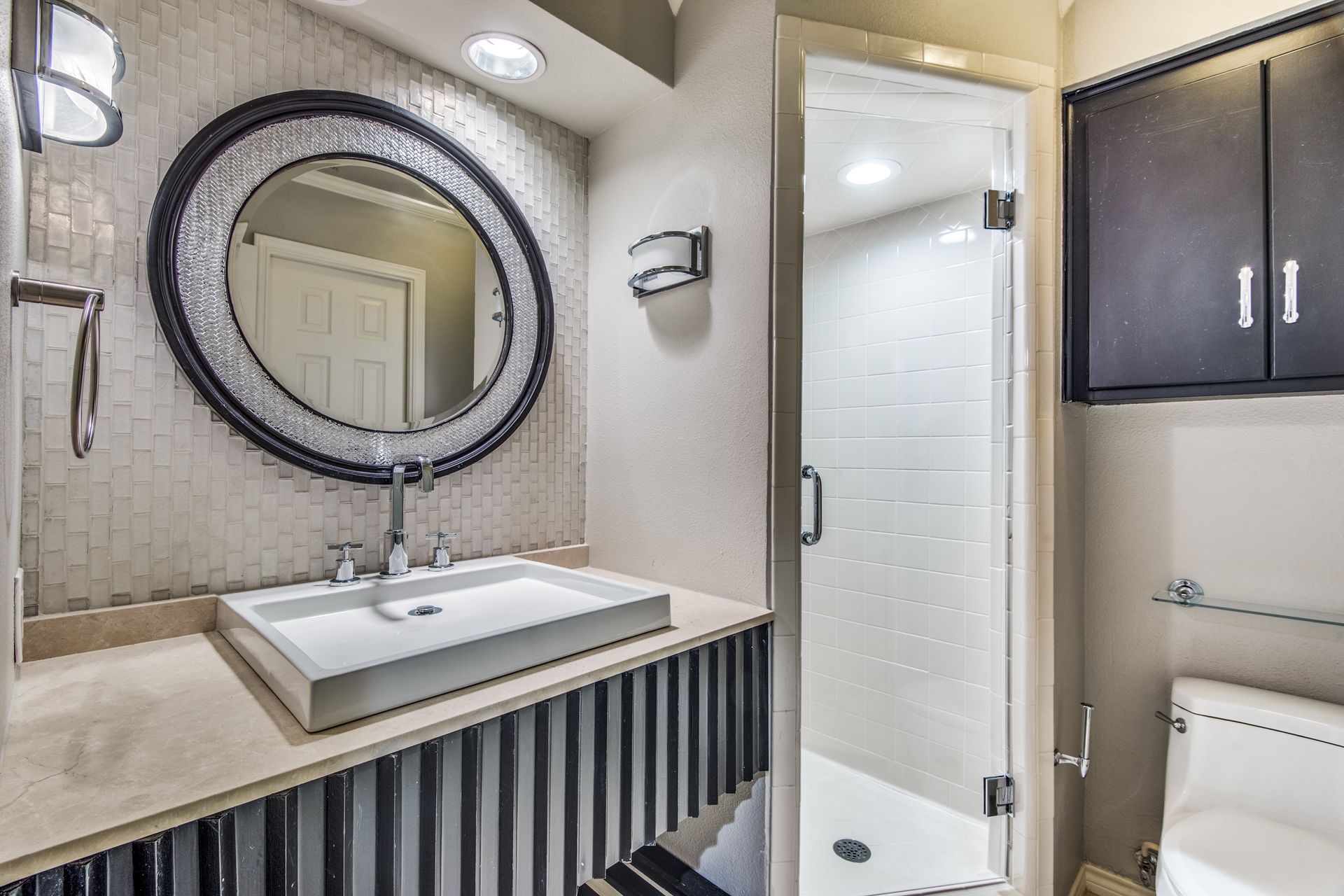 A bathroom remodel with a sink , toilet , shower and mirror.