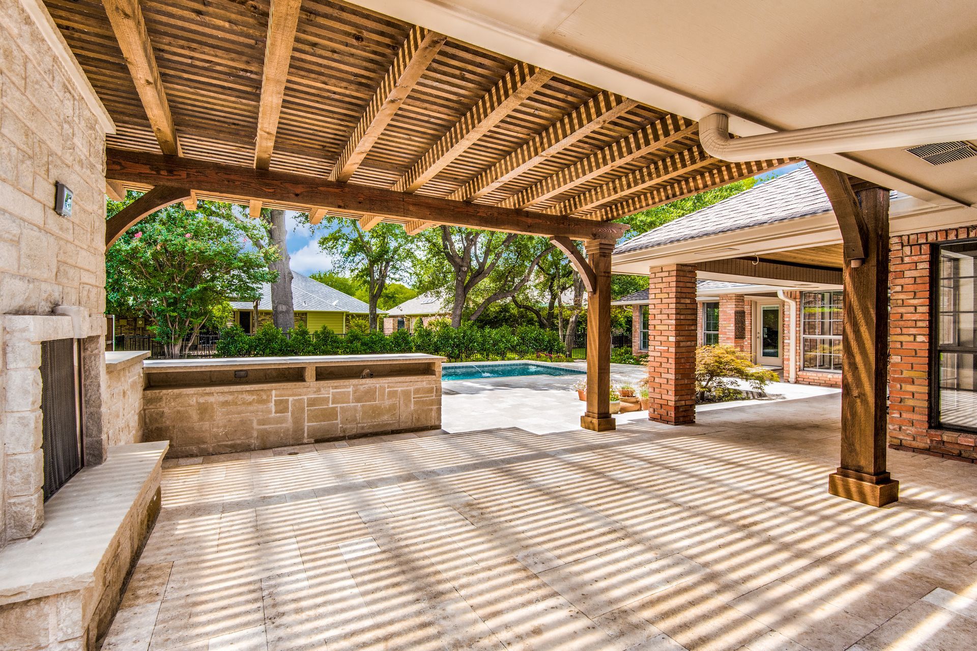 A large patio remodel with a wooden pergola and a fireplace.