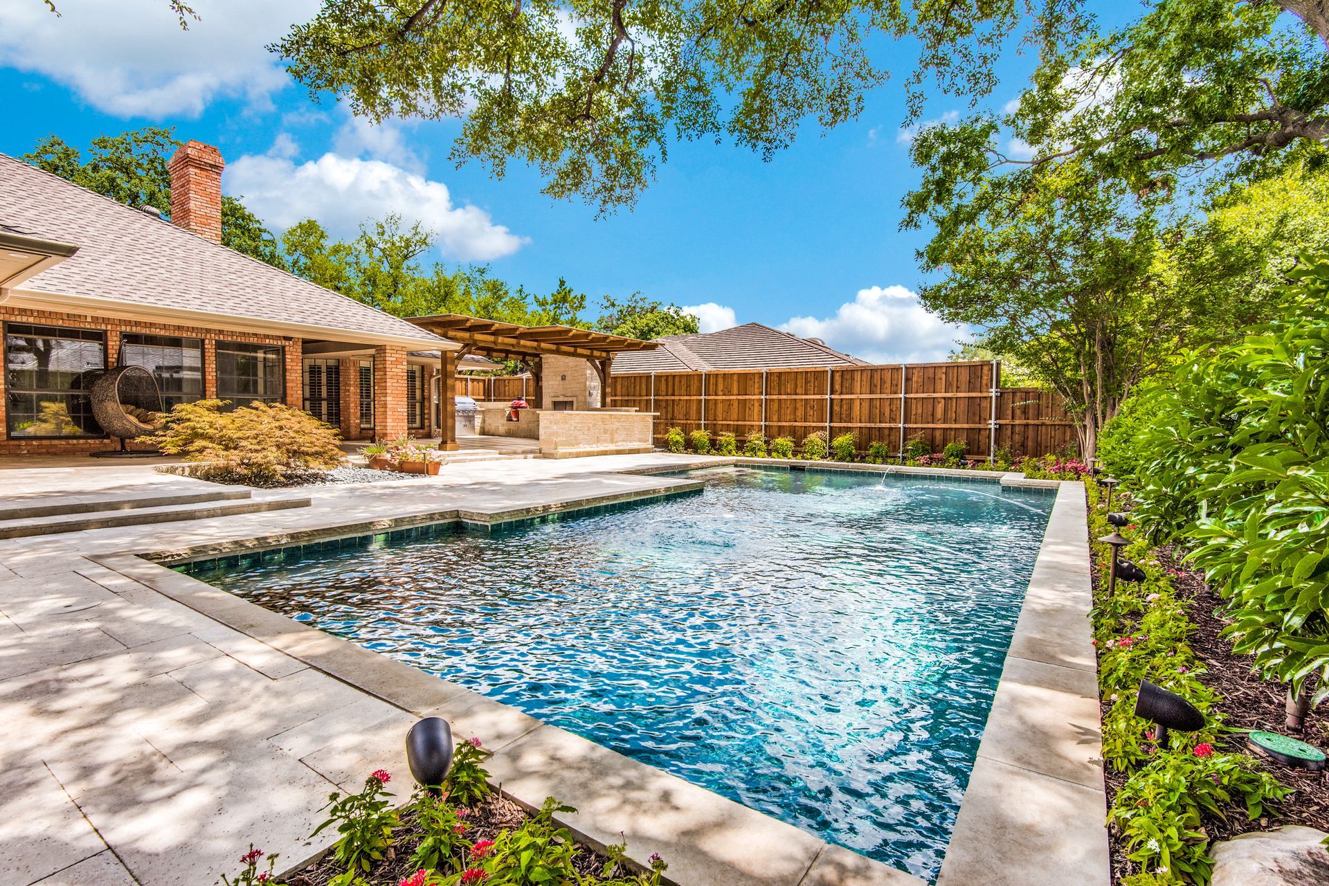 There is a large swimming pool in the backyard of a house.