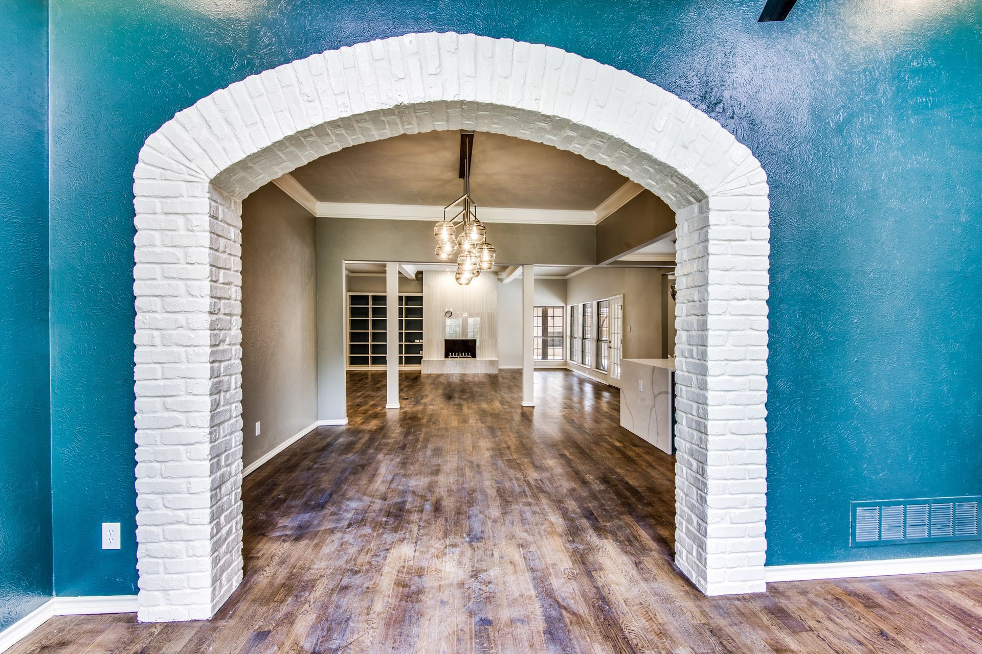 A room with a brick archway leading to a dining room.