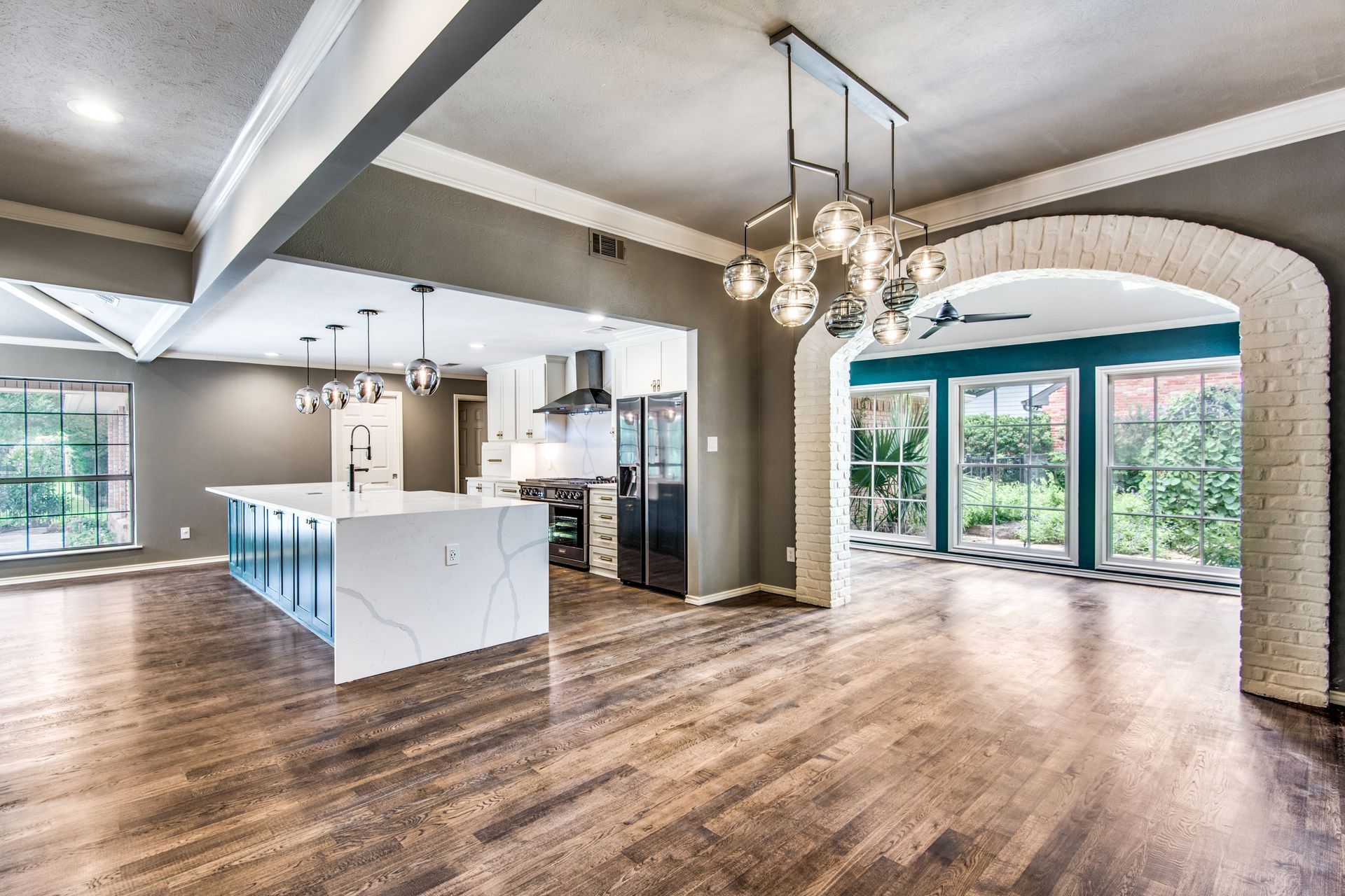 A large empty room with hardwood floors and a kitchen.