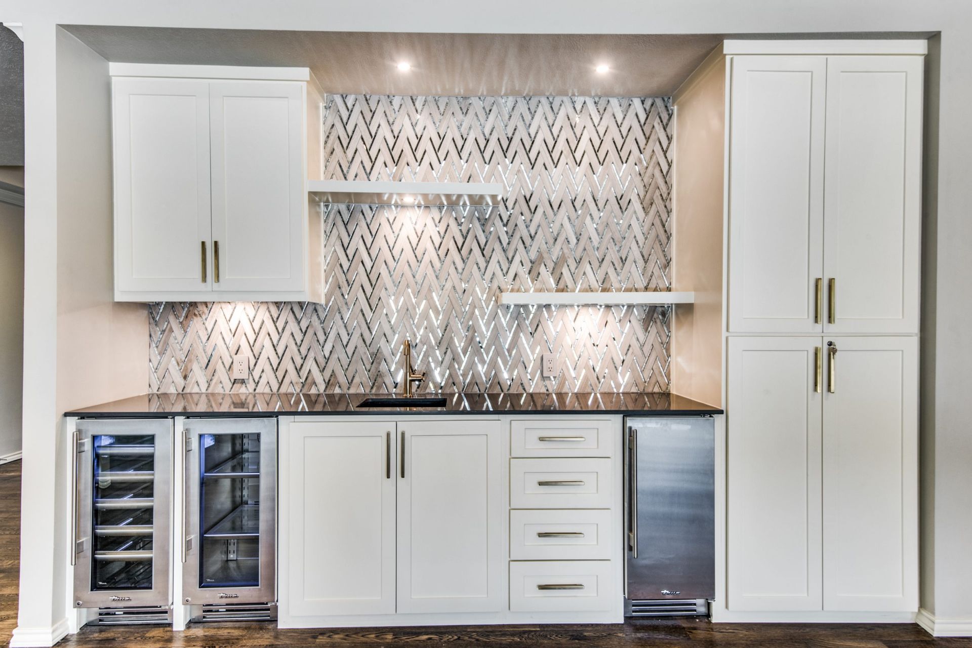 A Plano home remodel kitchen with white cabinets , stainless steel appliances and a wine cooler.