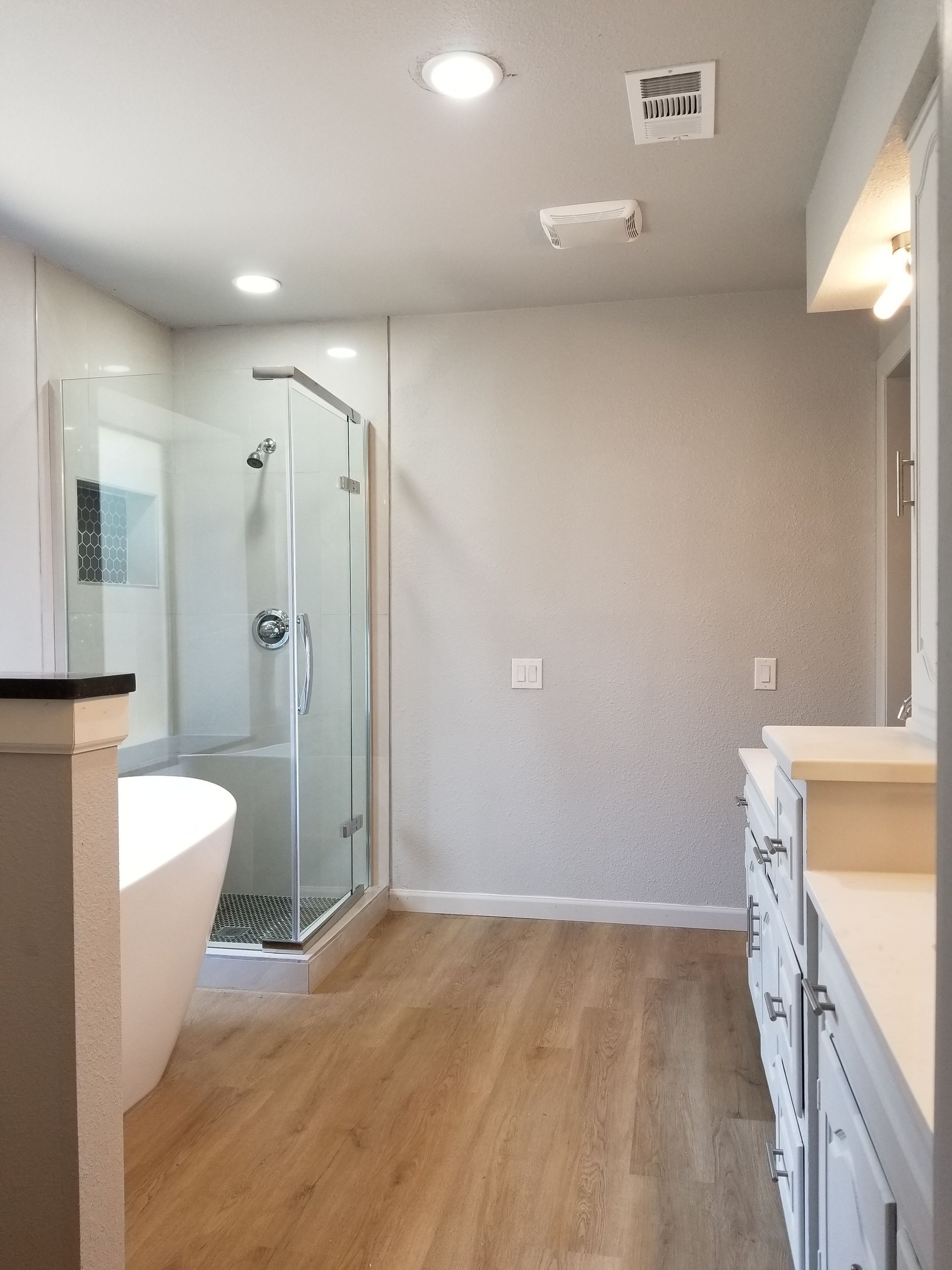 A bathroom remodel with hardwood floors and a walk in shower