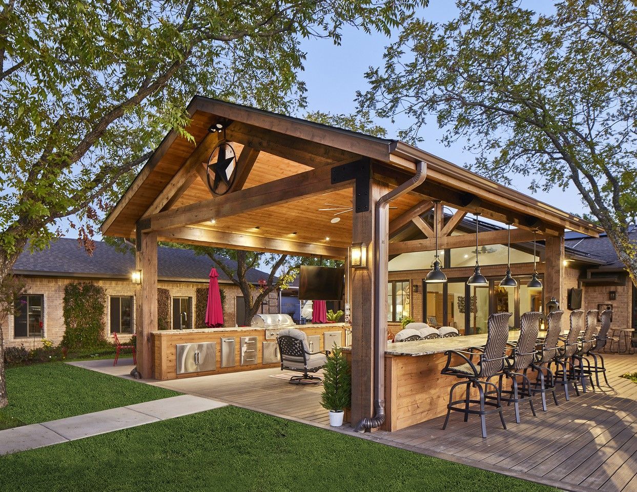 A large wooden pavilion remodel with a bar and chairs underneath it.