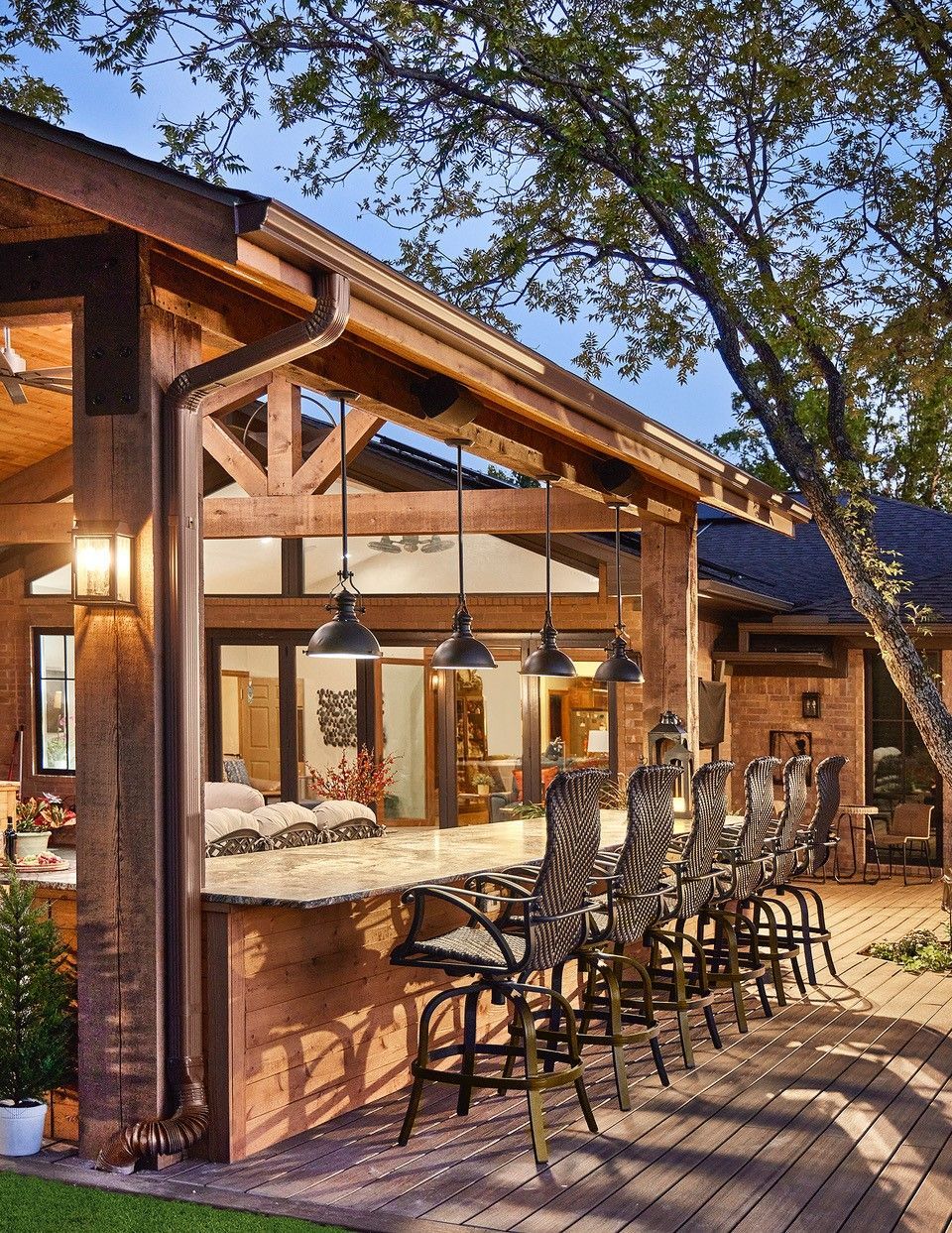 A brick house with a bar and chairs in front of a bar under the pavilion remodel