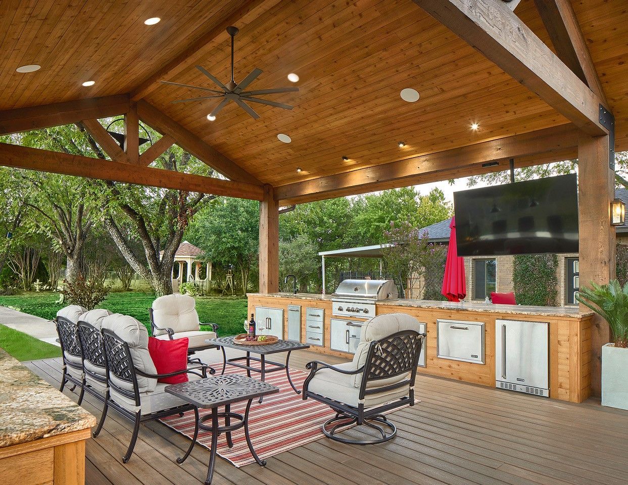 A large wooden deck remodel with a ceiling fan and a television.