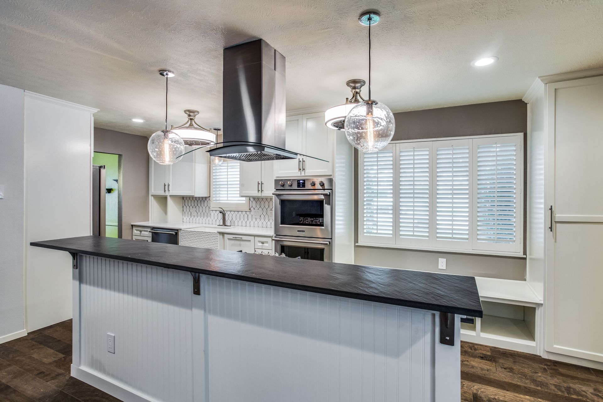 A kitchen with white cabinets , stainless steel appliances , and a large island.