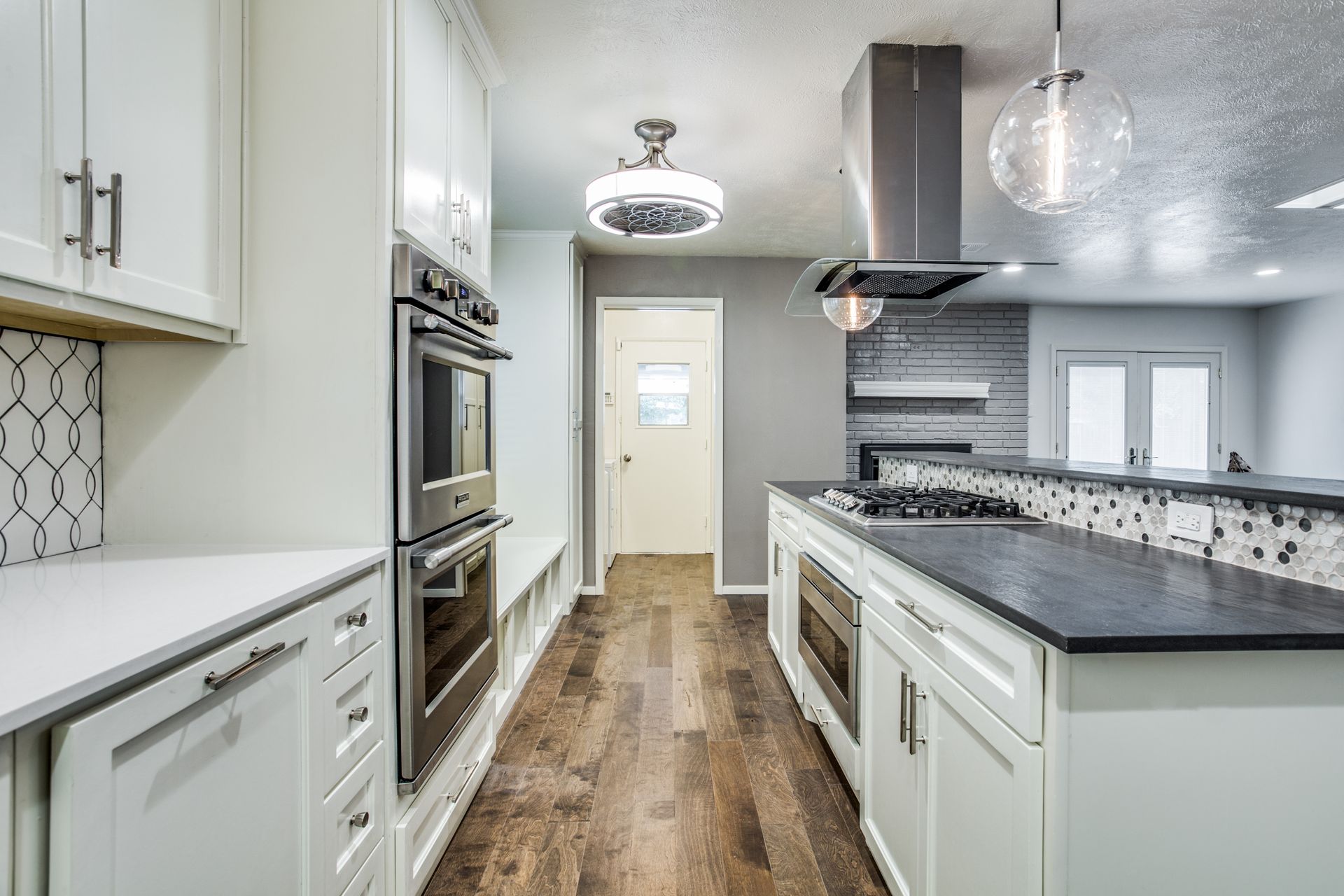 A kitchen with white cabinets , black counter tops , and stainless steel appliances.