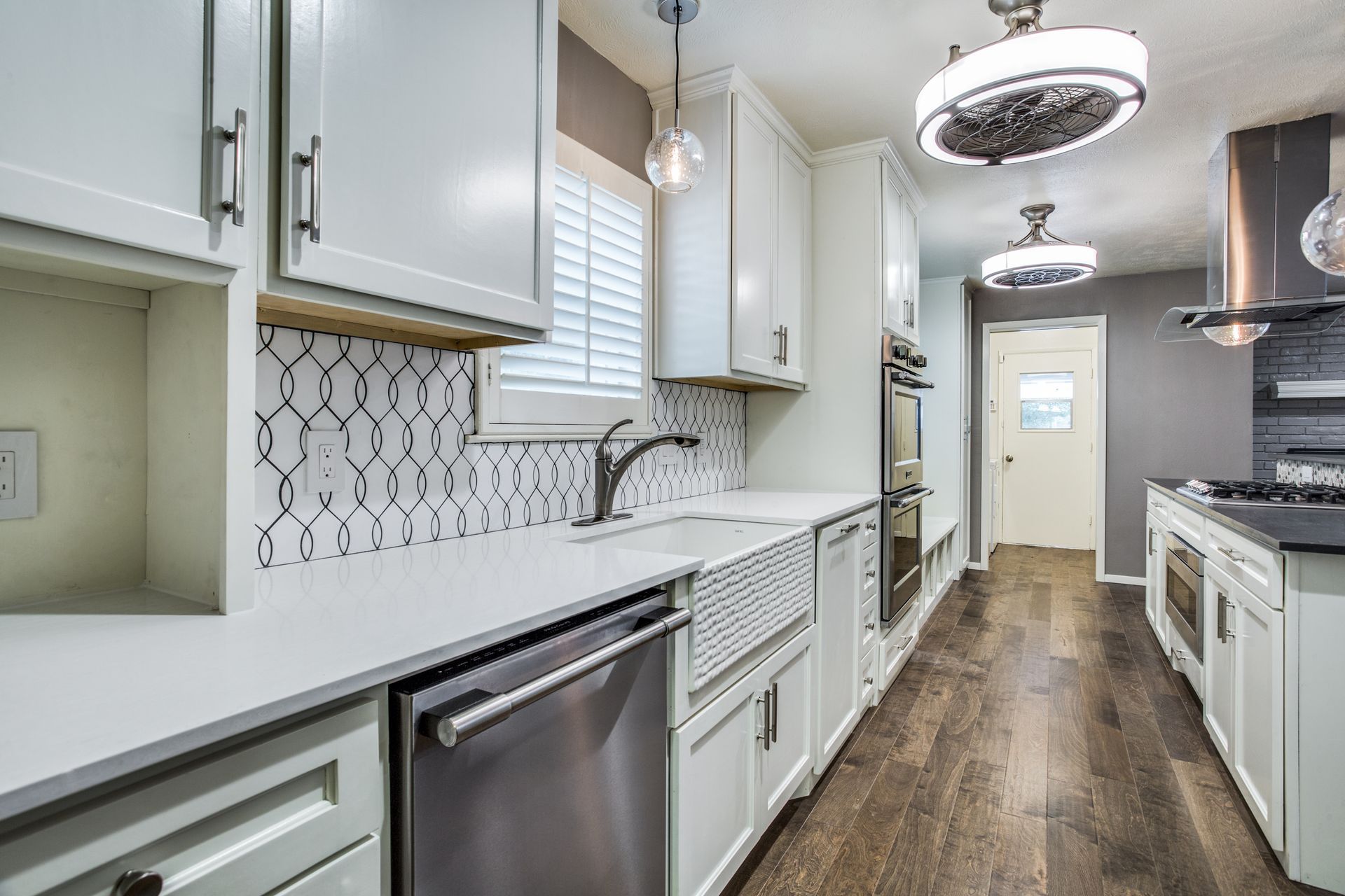 A long kitchen with white cabinets and stainless steel appliances.