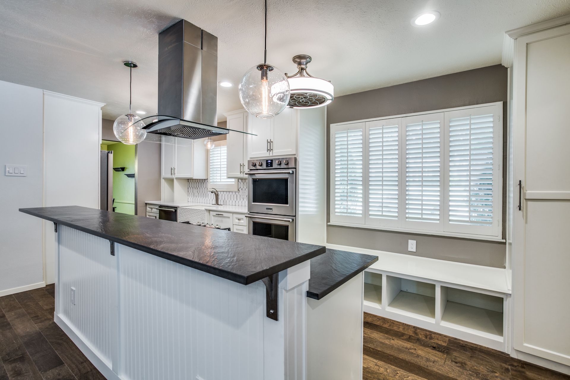 A kitchen with white cabinets , stainless steel appliances , and a black counter top.