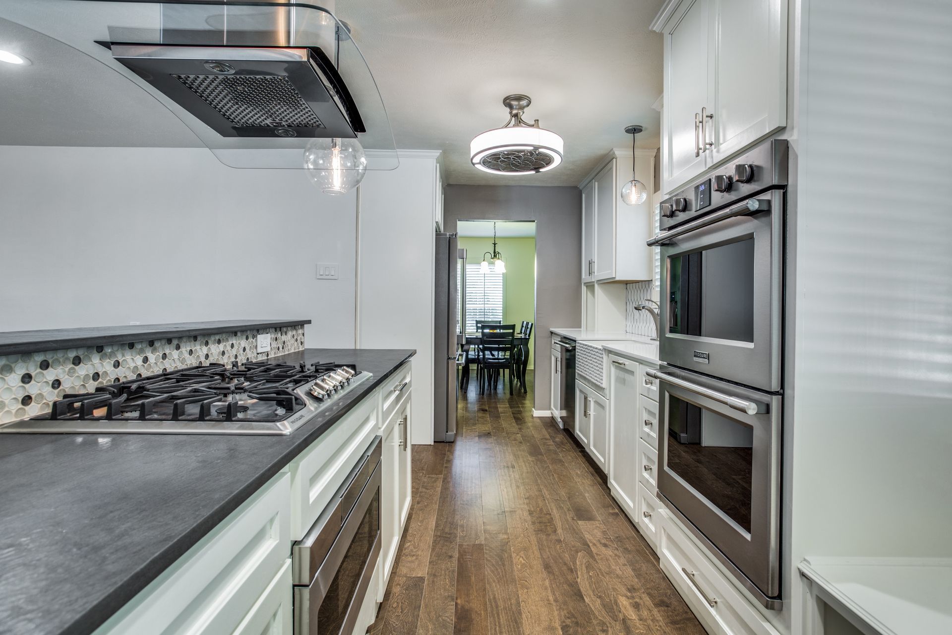 A long kitchen with stainless steel appliances and white cabinets.