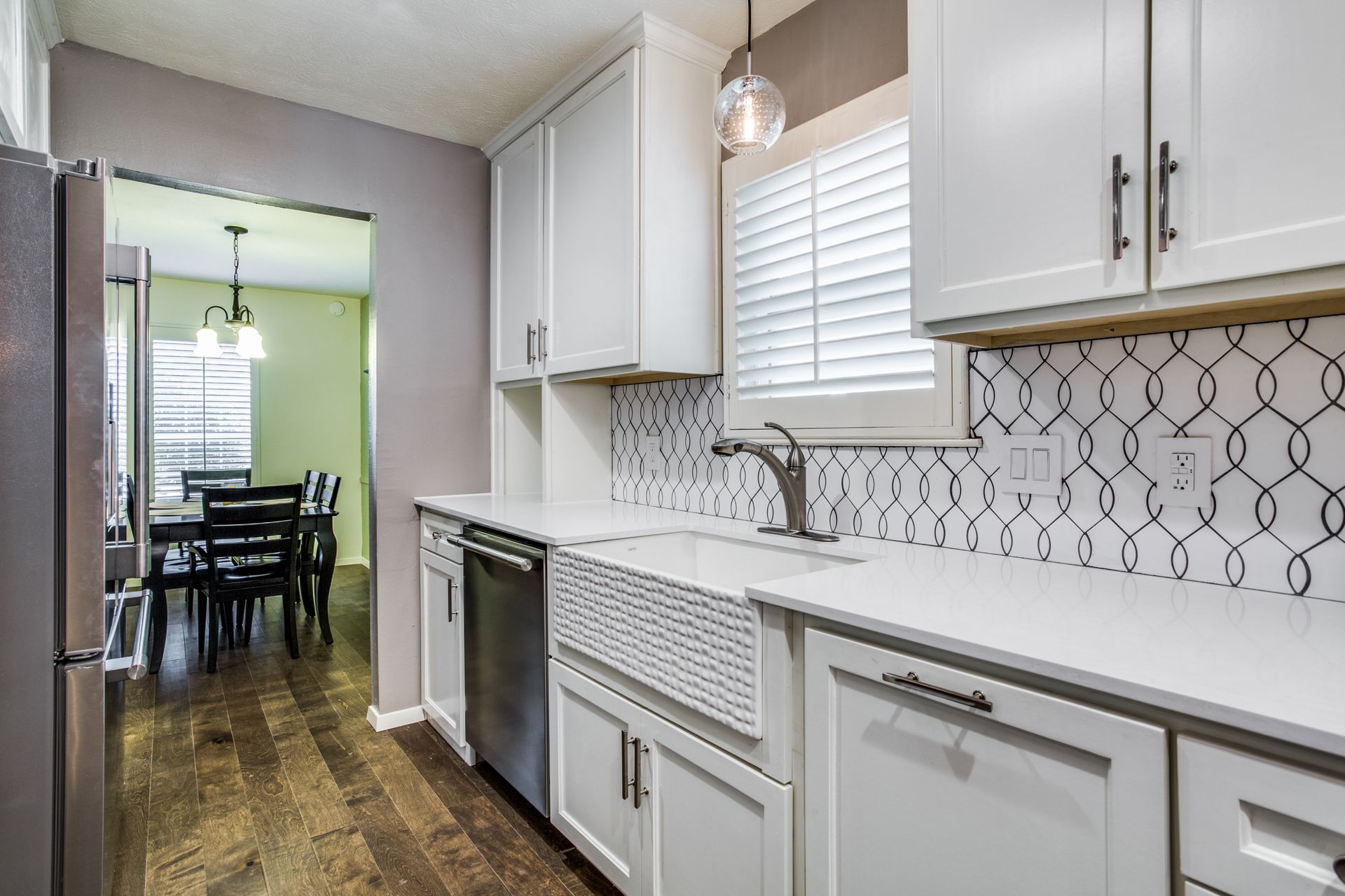 A kitchen with white cabinets , a sink , and a dishwasher.