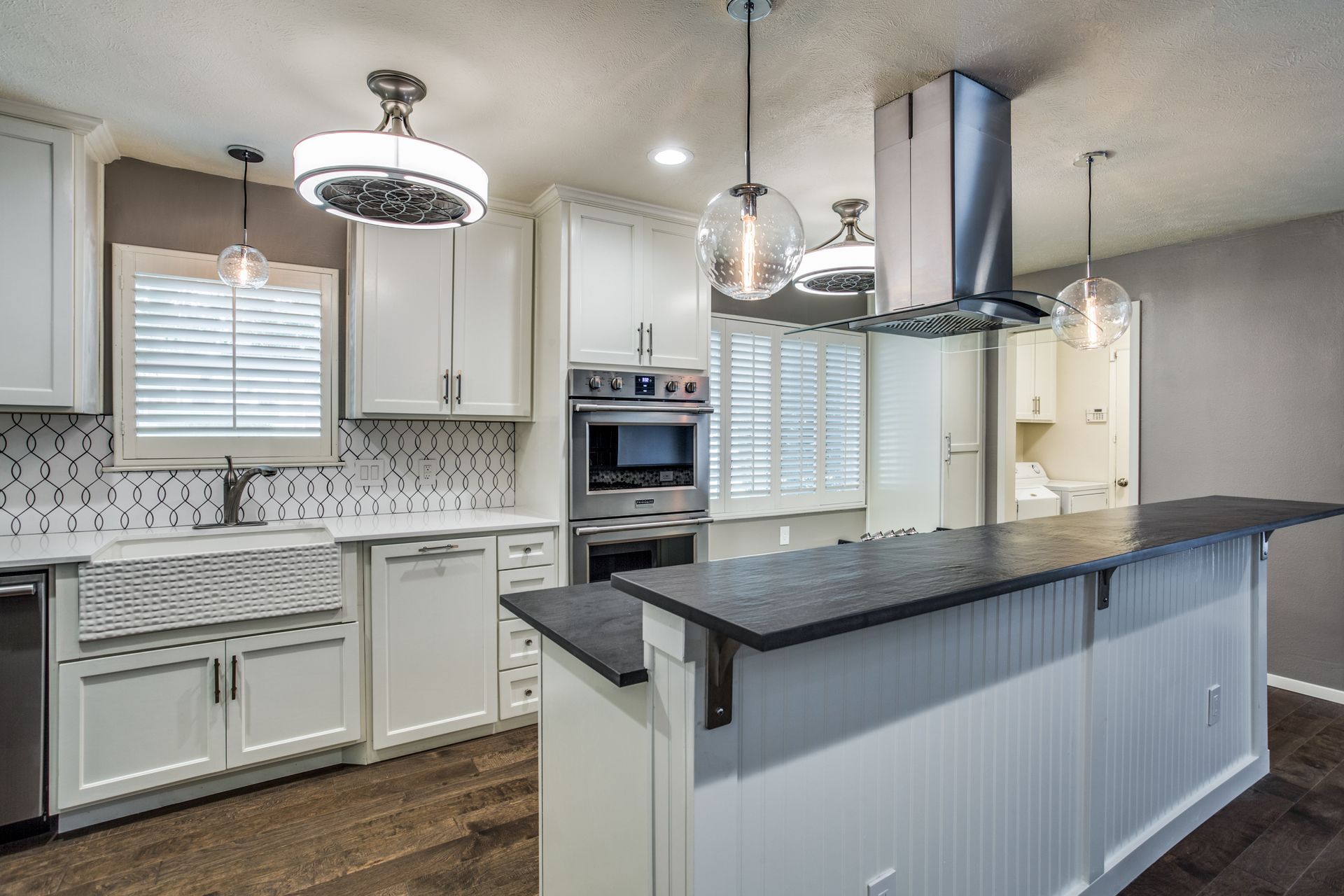 A kitchen with white cabinets , stainless steel appliances , and a large island.