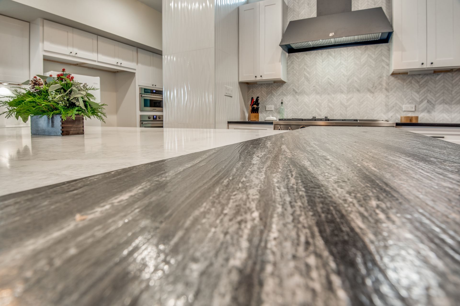 A kitchen with a granite counter top and white cabinets.