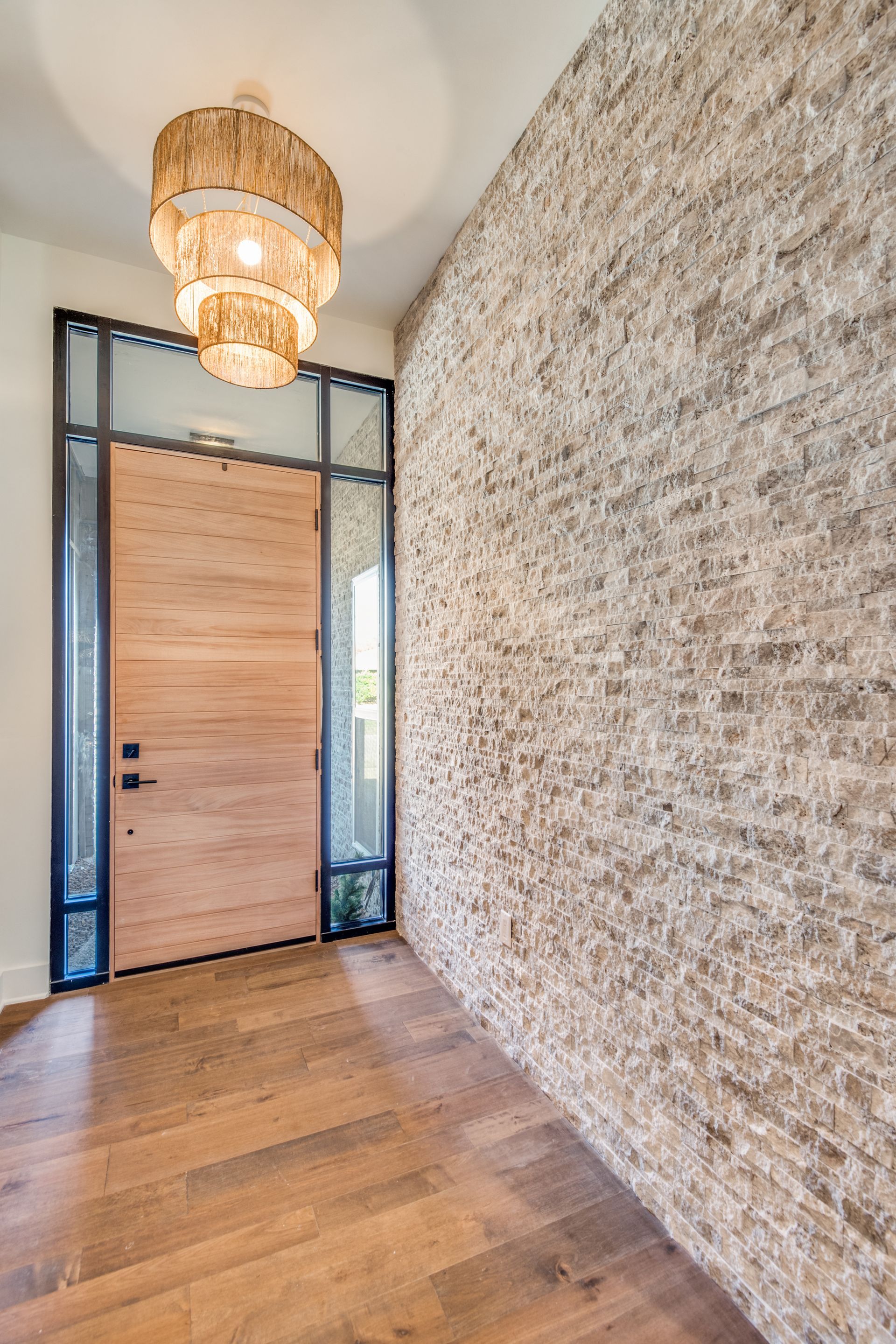 A plano home remodel hallway with a wooden door and a brick wall.