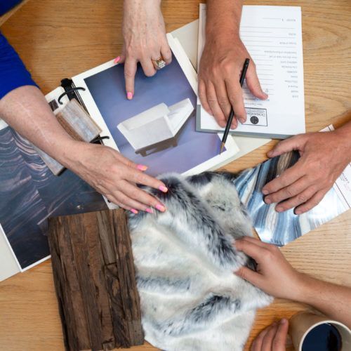 A group of people are sitting at a table looking at pictures and papers