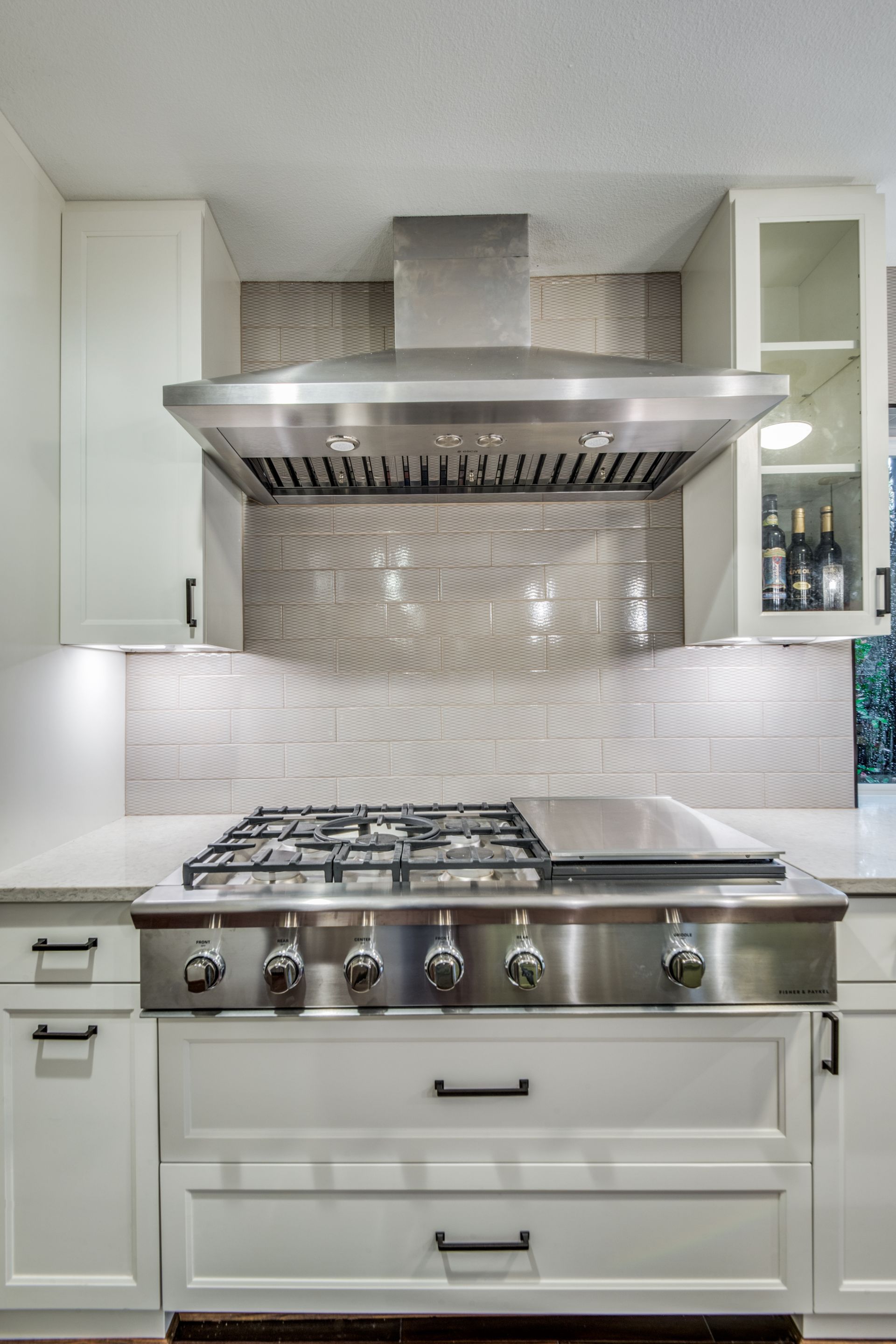 A kitchen with a stove top oven and a hood above it.