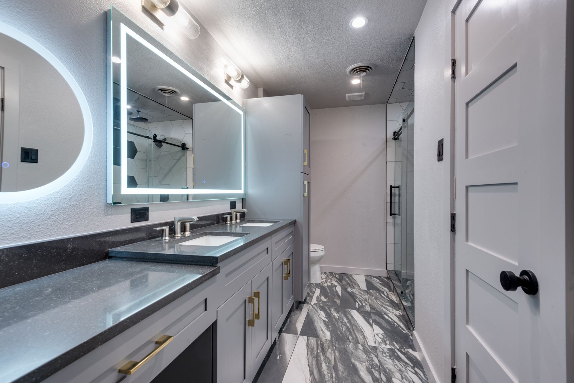 A bathroom with two sinks , a mirror and a toilet.