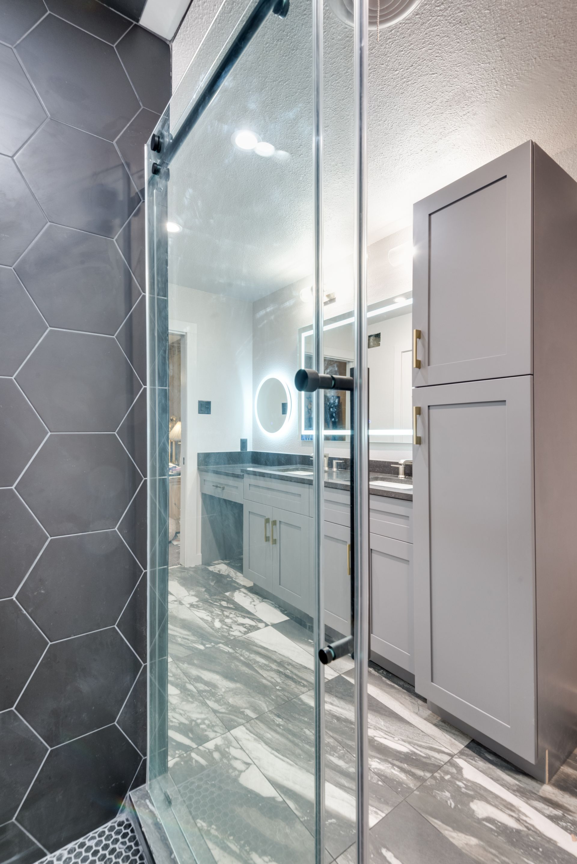 A bathroom with a walk in shower and a vanity.