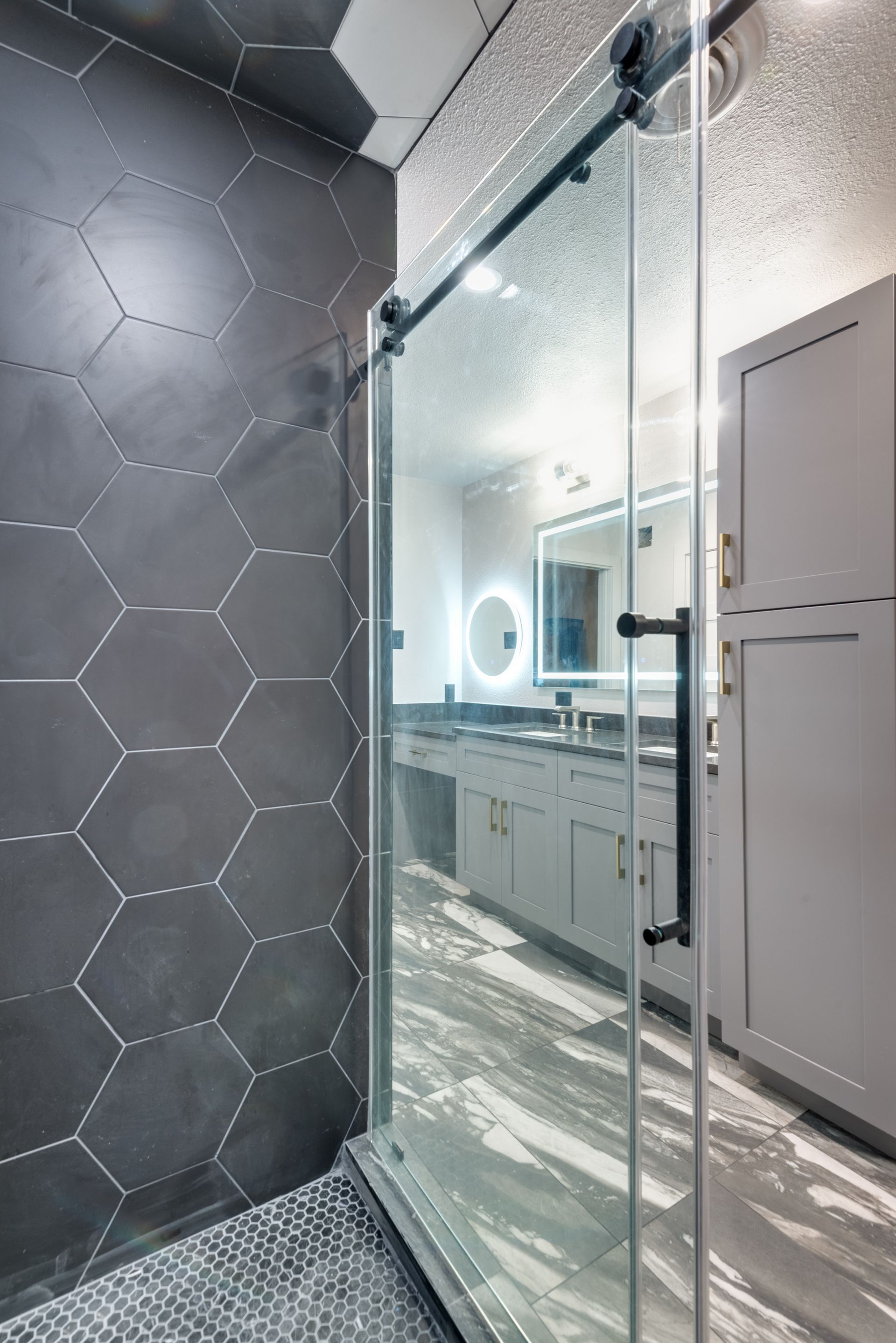 A bathroom with a sliding glass shower door and a mirror.