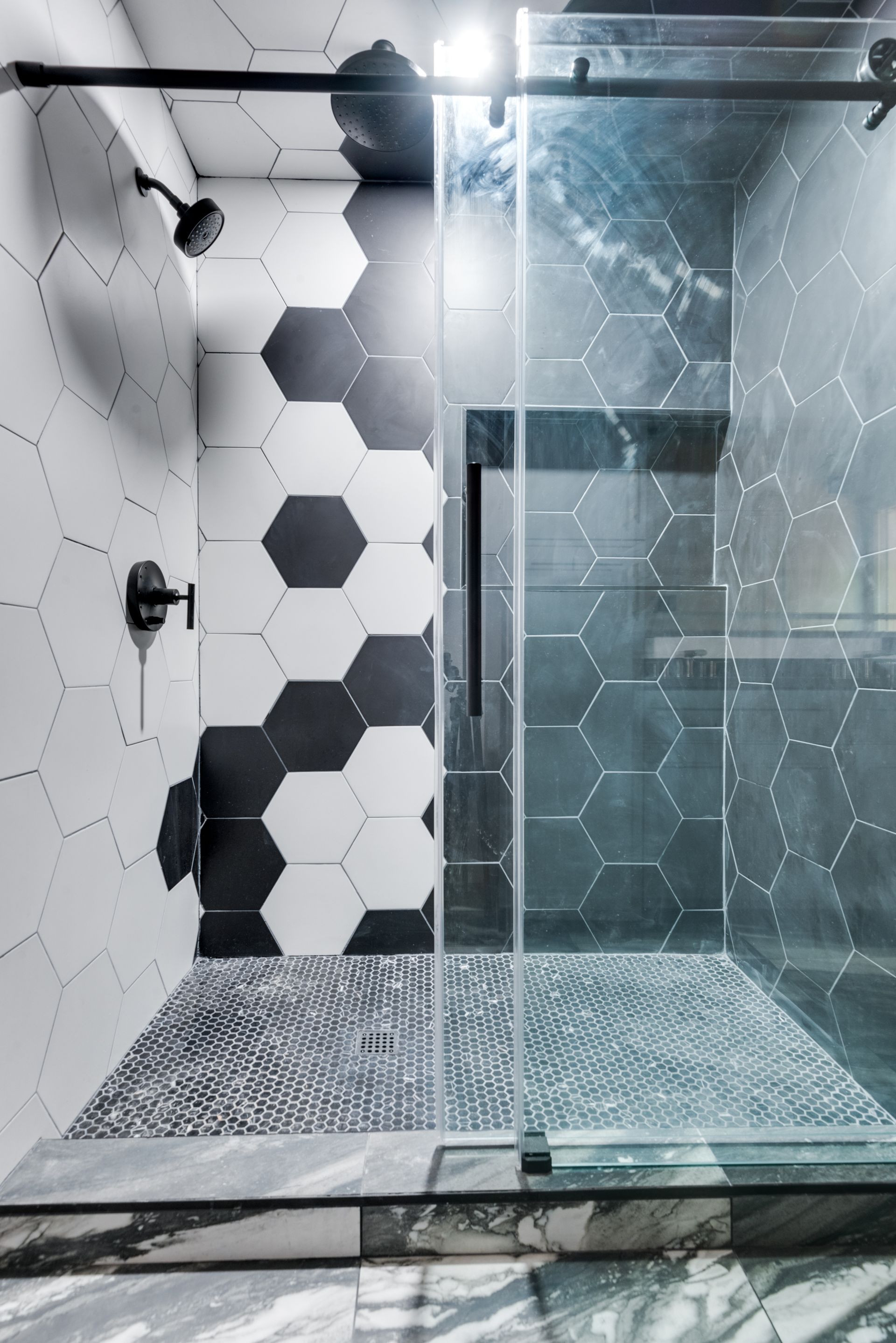 A bathroom with black and white tiles and a walk in shower.