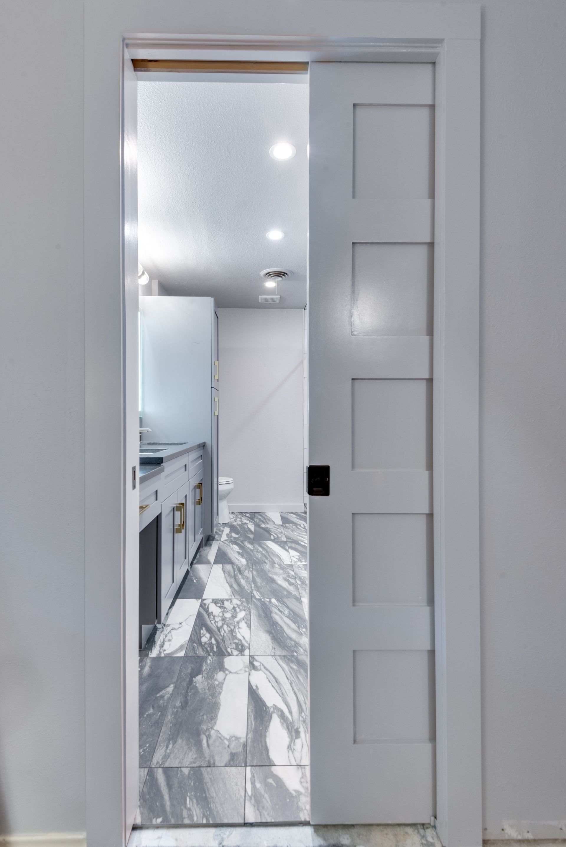 A white sliding door is open to a bathroom.
