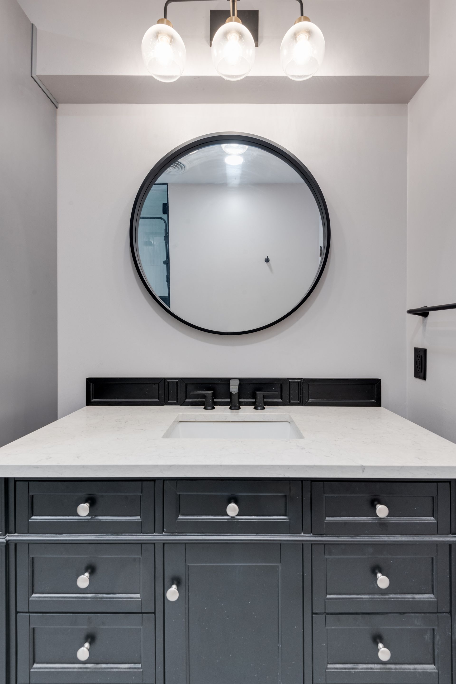 A bathroom remodel sink with a round mirror above it.
