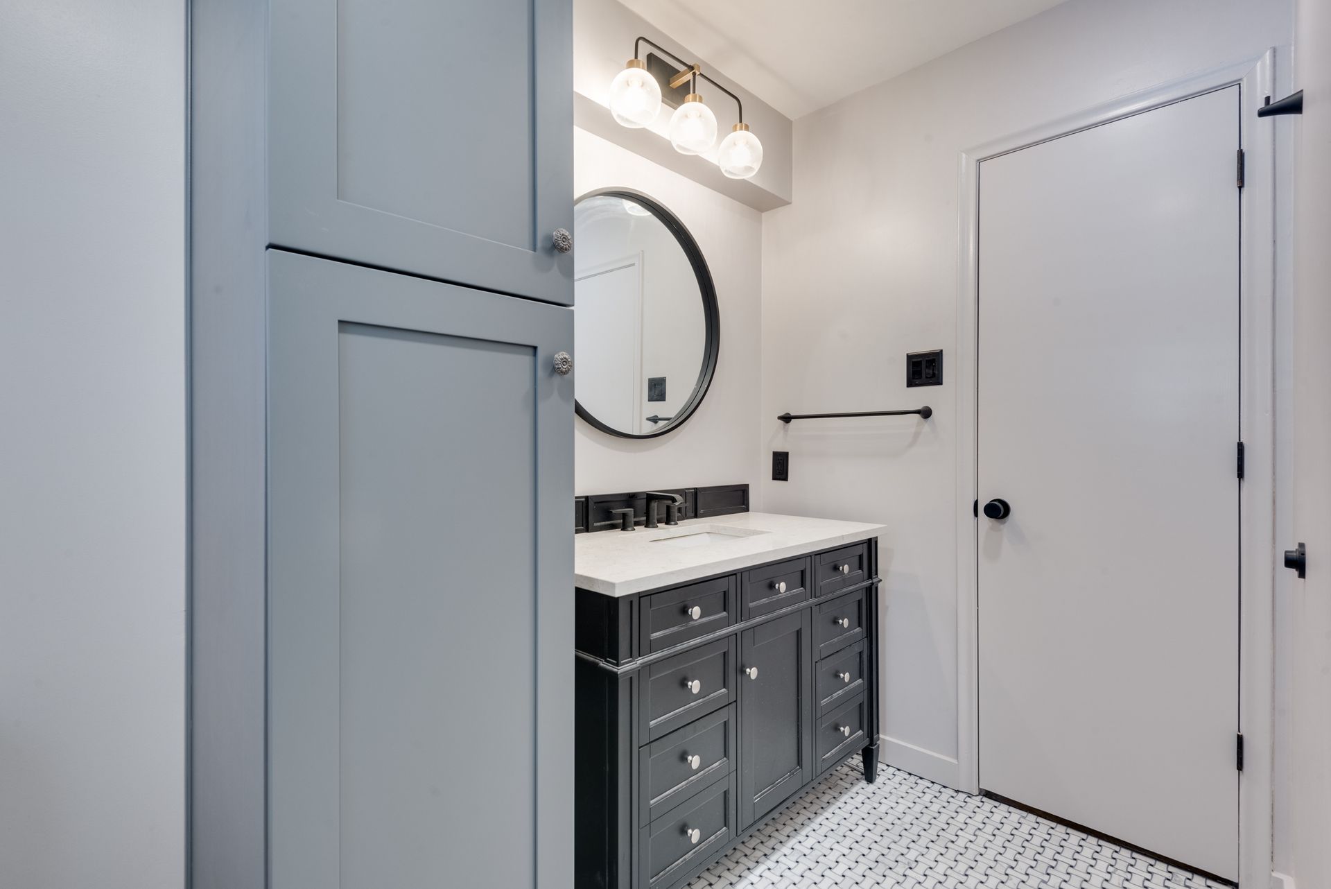 A bathroom with a sink , mirror and cabinets.