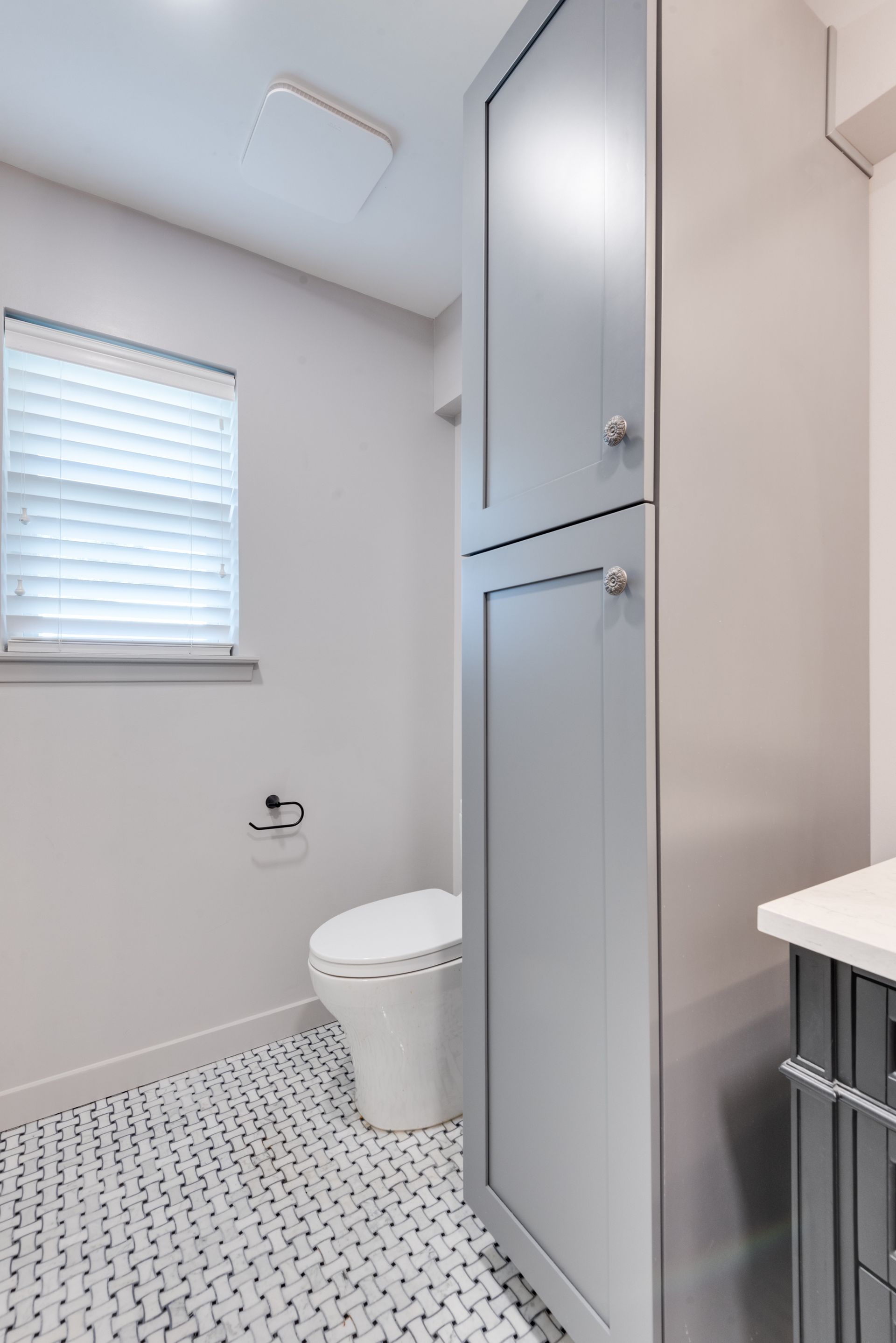 A bathroom with a toilet , sink and window.