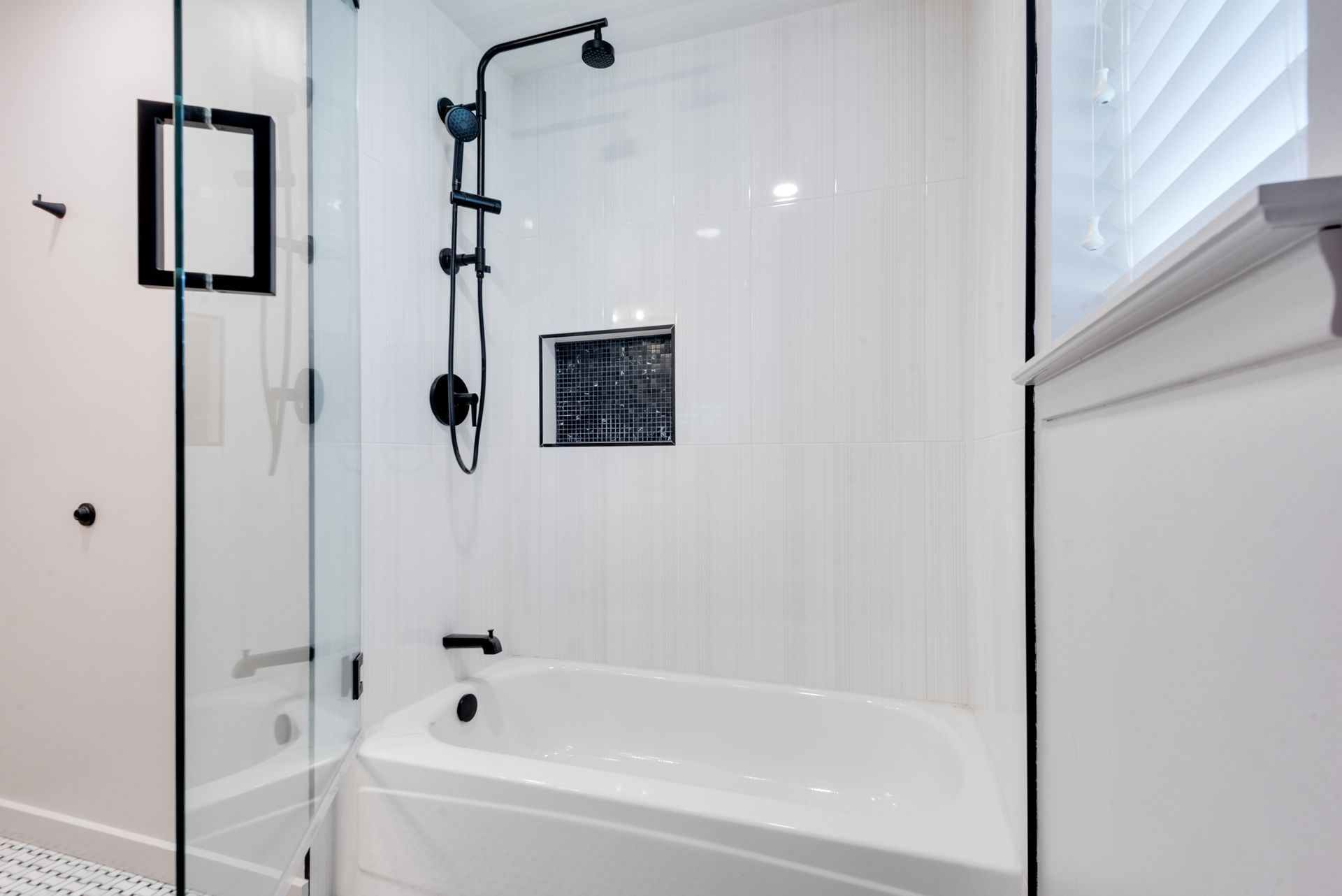 A bathroom with a tub , shower , and window.
