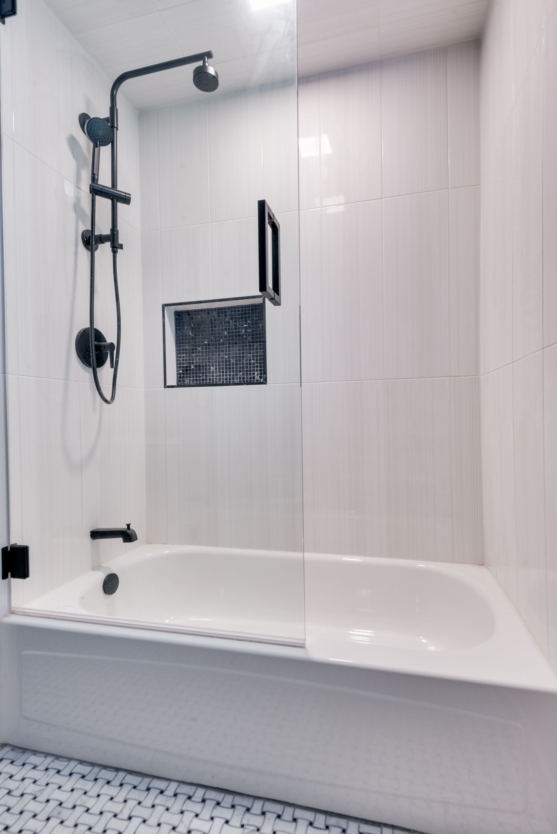 A bathroom with a bathtub and a shower with a glass door.