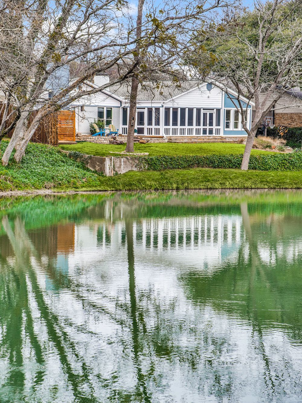 A house is reflected in a pond with trees in the background.