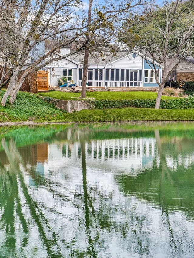 A house is reflected in a pond with trees in the background.
