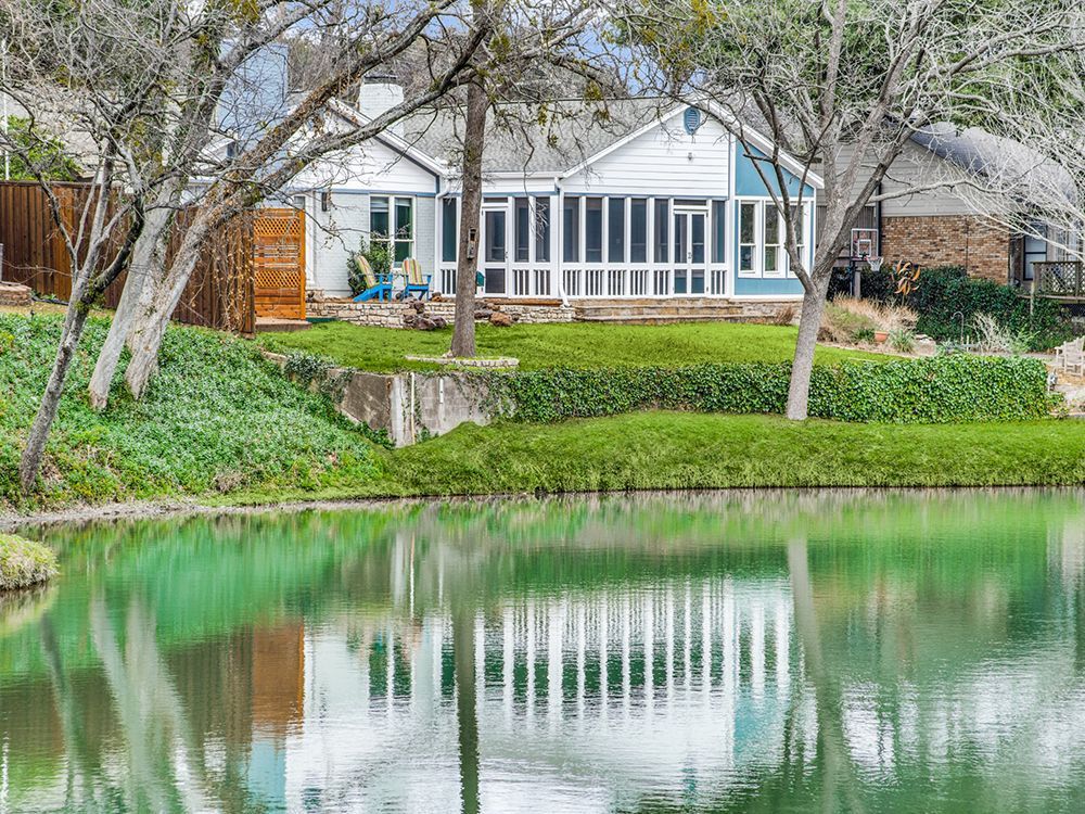 A house is reflected in a pond in front of it.