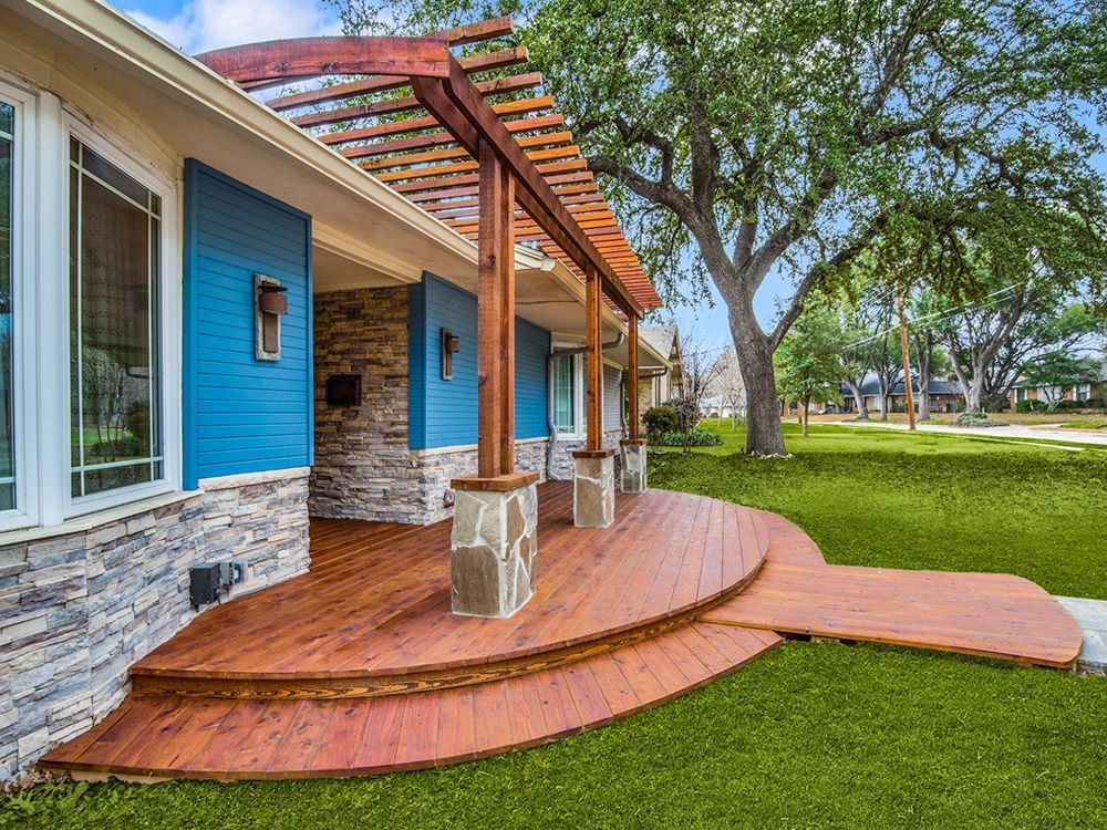 A blue house remodel  with a wooden deck and a pergola.
