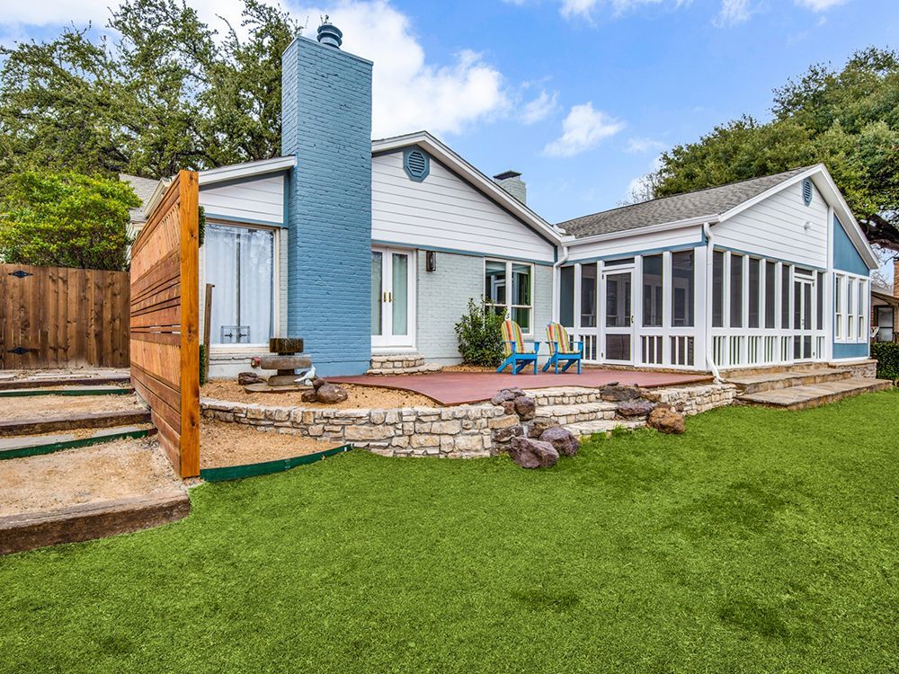 A house remodel  with a screened in porch and a large lawn in front of it.
