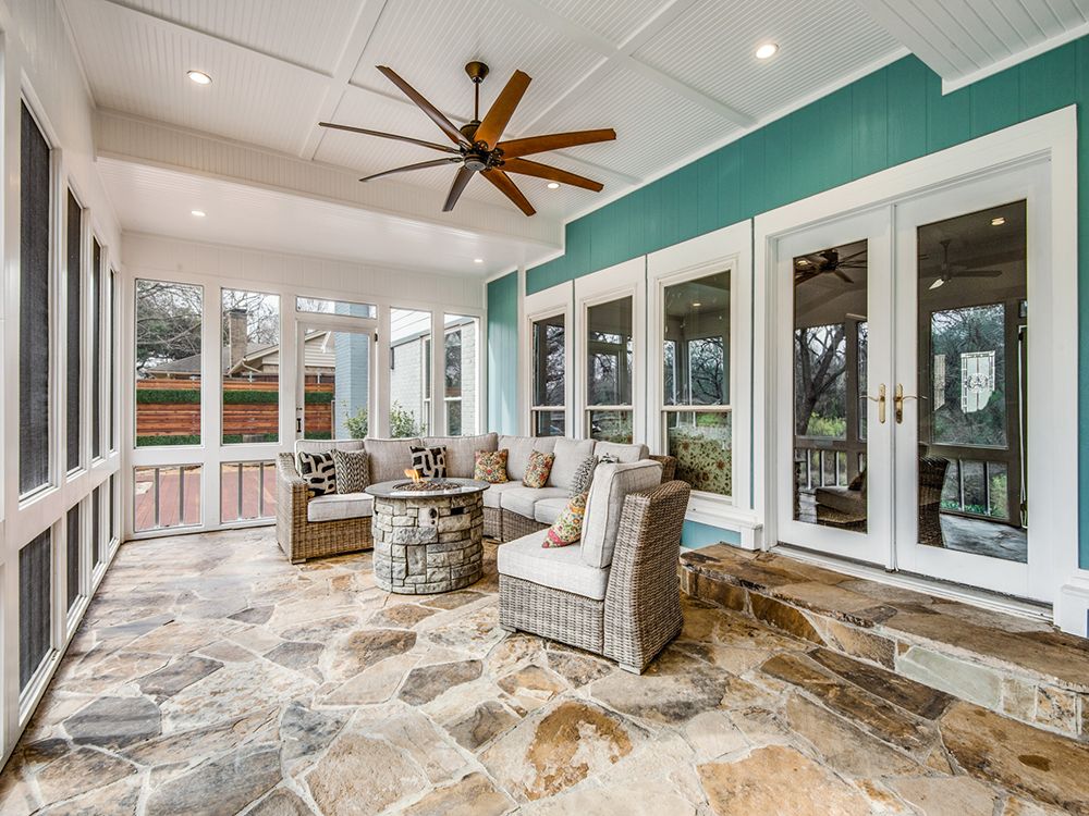 A screened in sunroom porch add on with a ceiling fan and a lot of windows.
