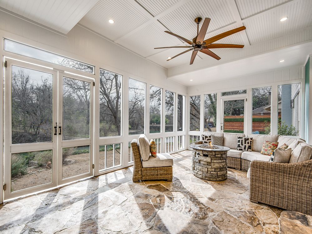 A sun room add on with a lot of windows and a ceiling fan.