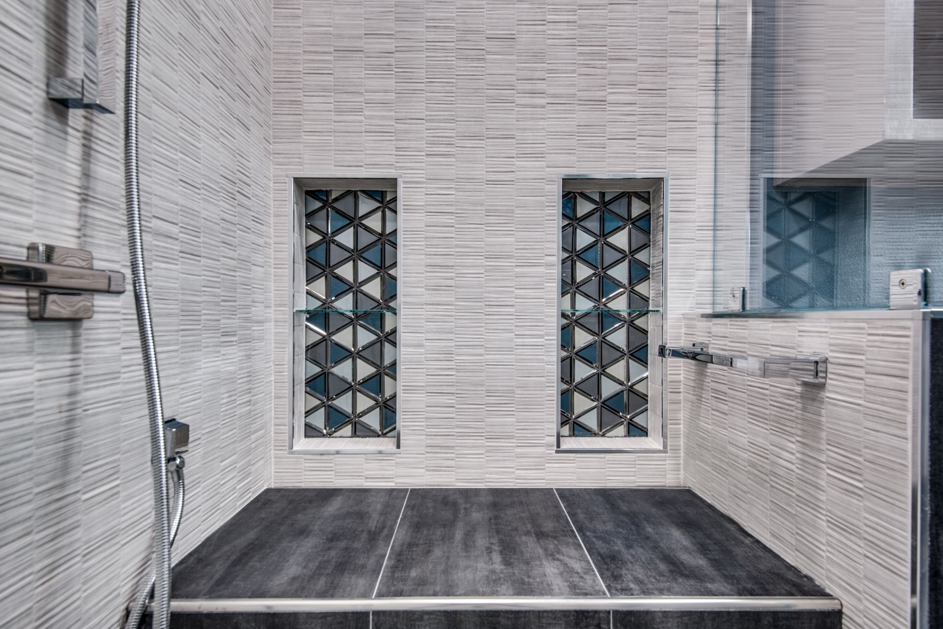 A bathroom remodel with a walk in shower and two windows.