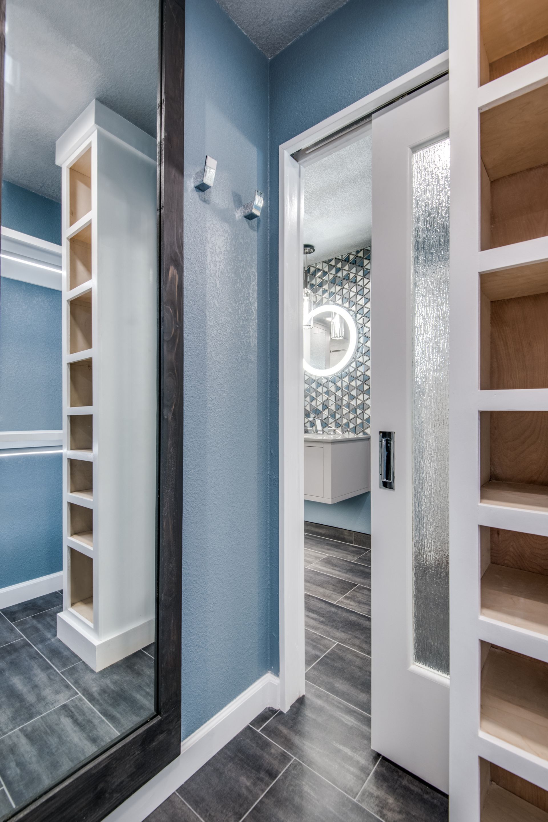 A walk in closet with a large mirror and sliding glass door leading to a bathroom remodel.