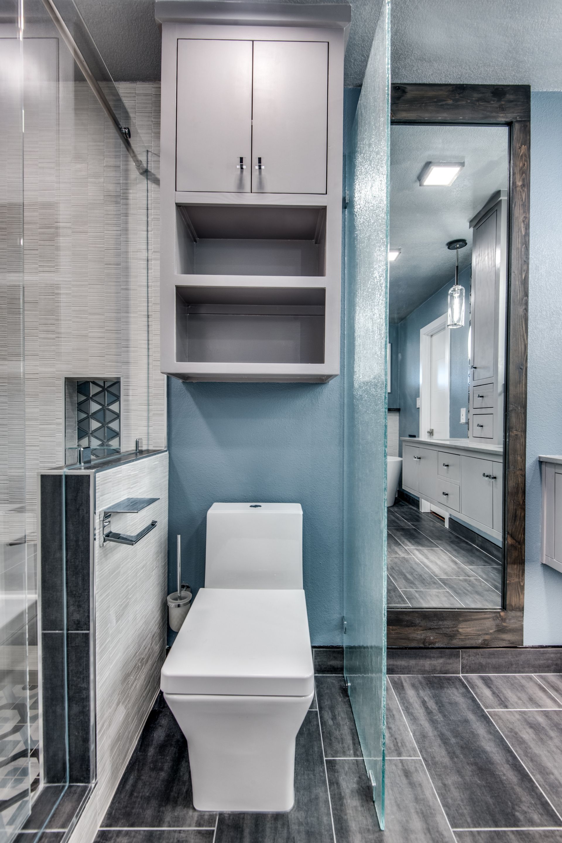 A bathroom remodel with a toilet , sink and mirror.
