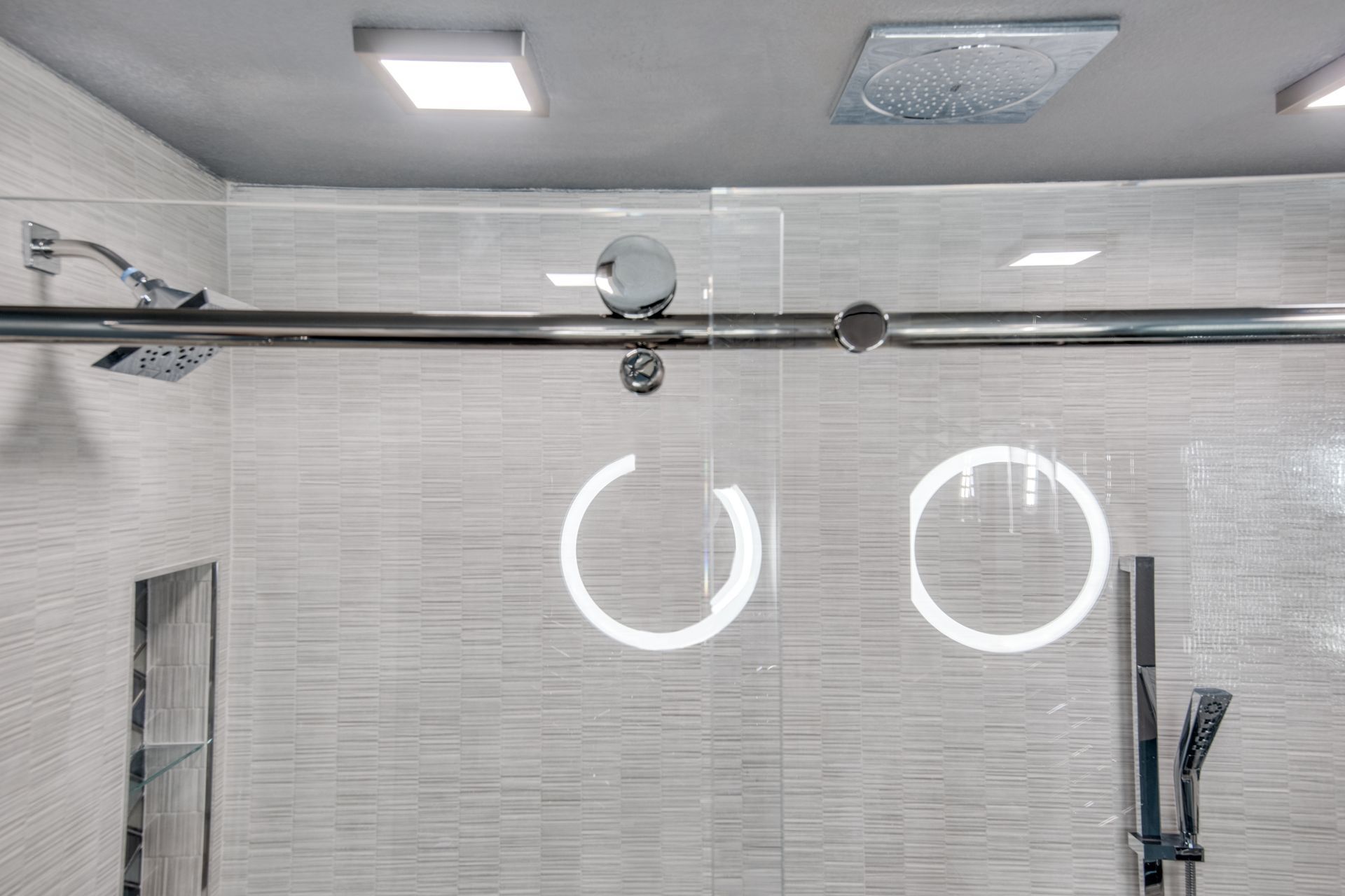 A bathroom remodel with a sliding glass shower door and two shower heads.