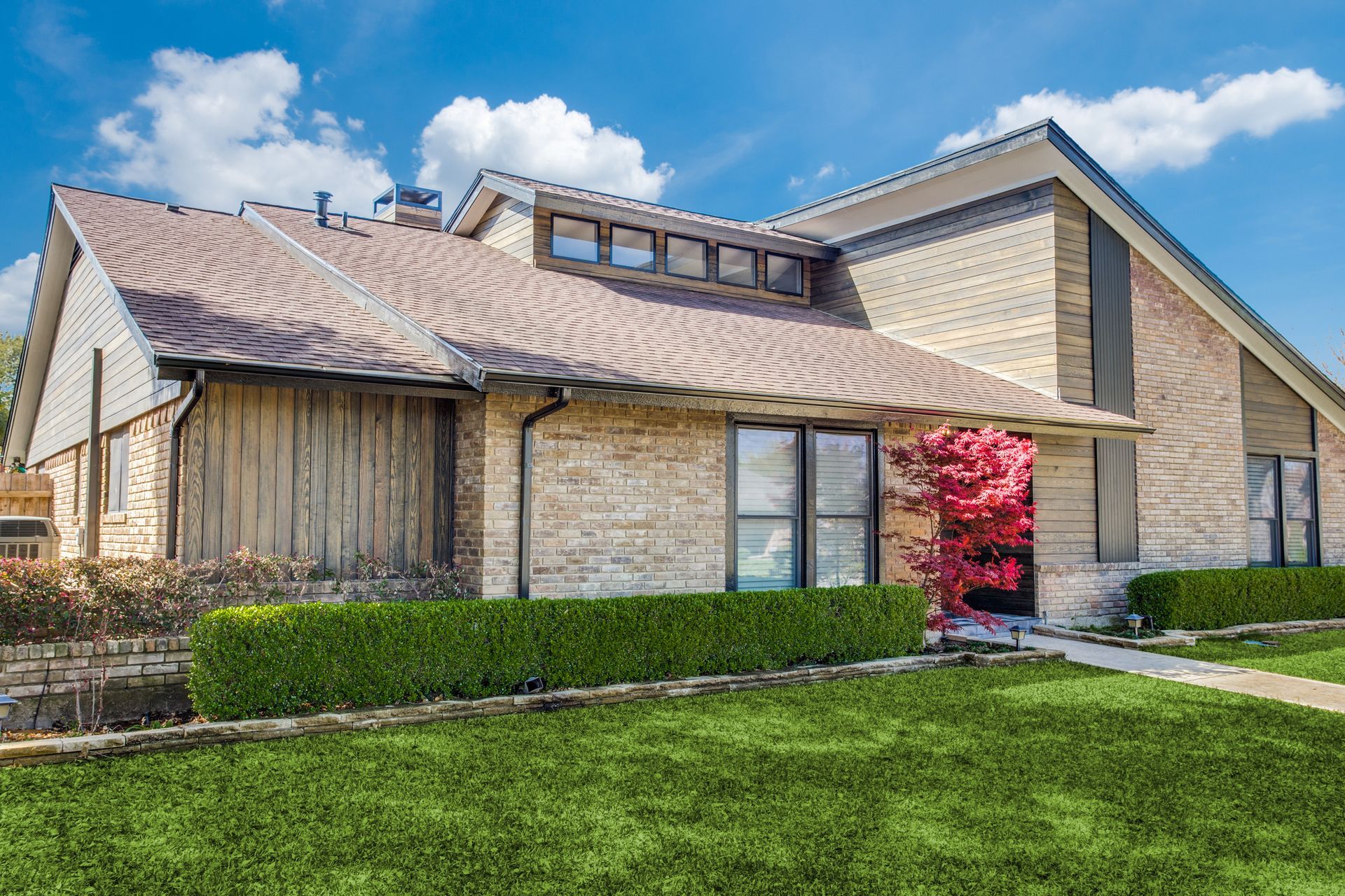 A large brick house remodel with a lush green lawn in front of it.