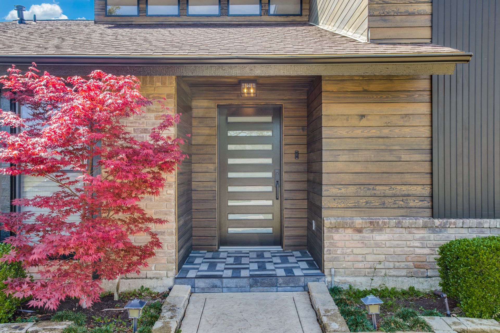 The front door of a house with a tree in front of it.