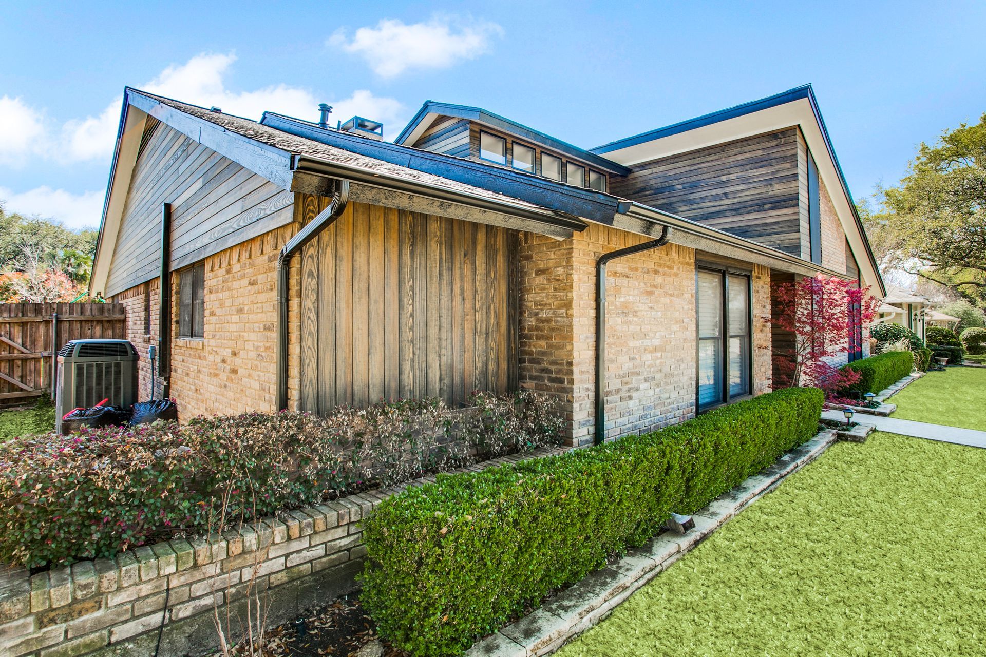 A brick house remodel with a blue roof and a green lawn.