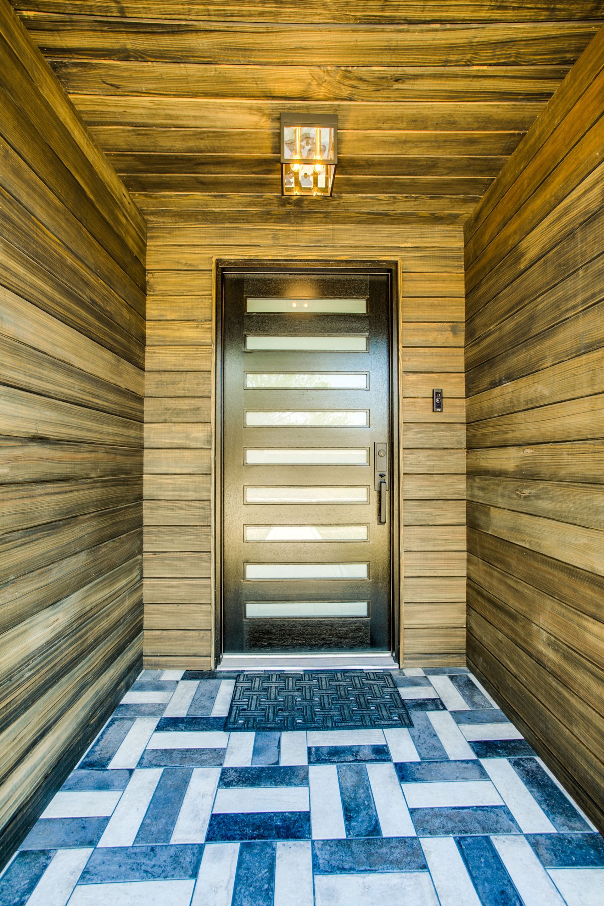 A front doorway with a rug on the floor and a wooden wall entrance remodel
