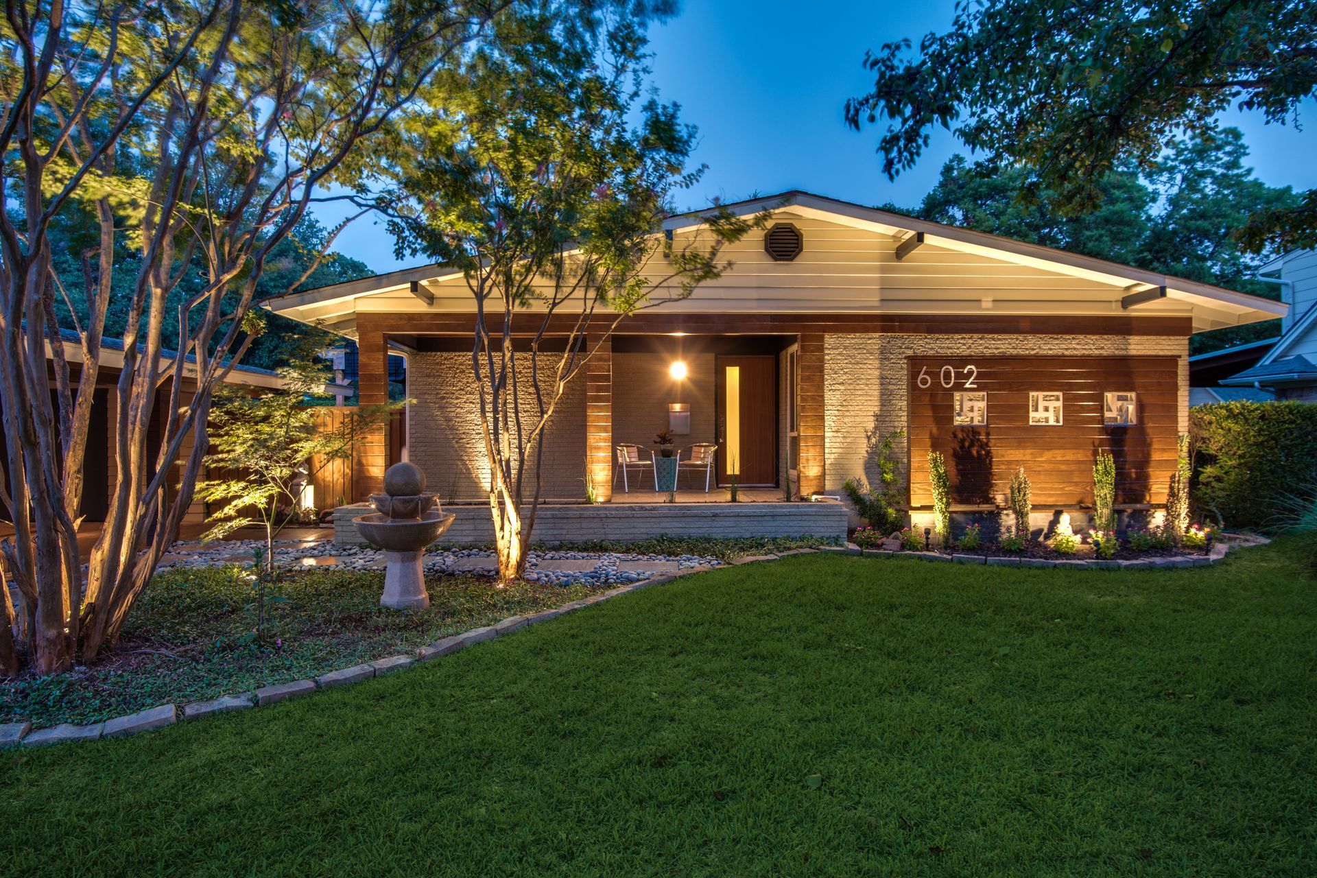 A house with a large lawn in front of it is lit up at night.