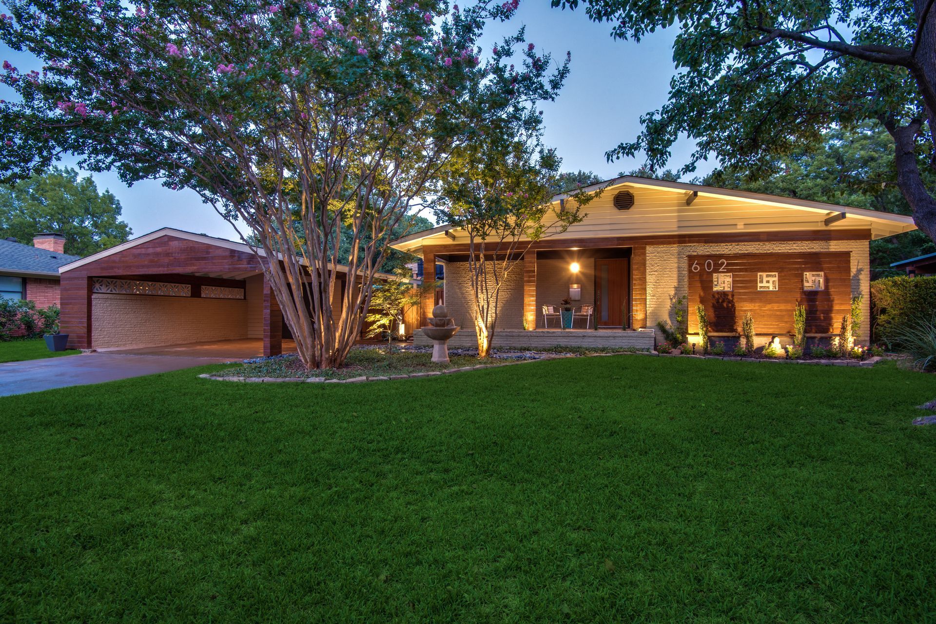 A house remodel with a lush green lawn and trees in front of it