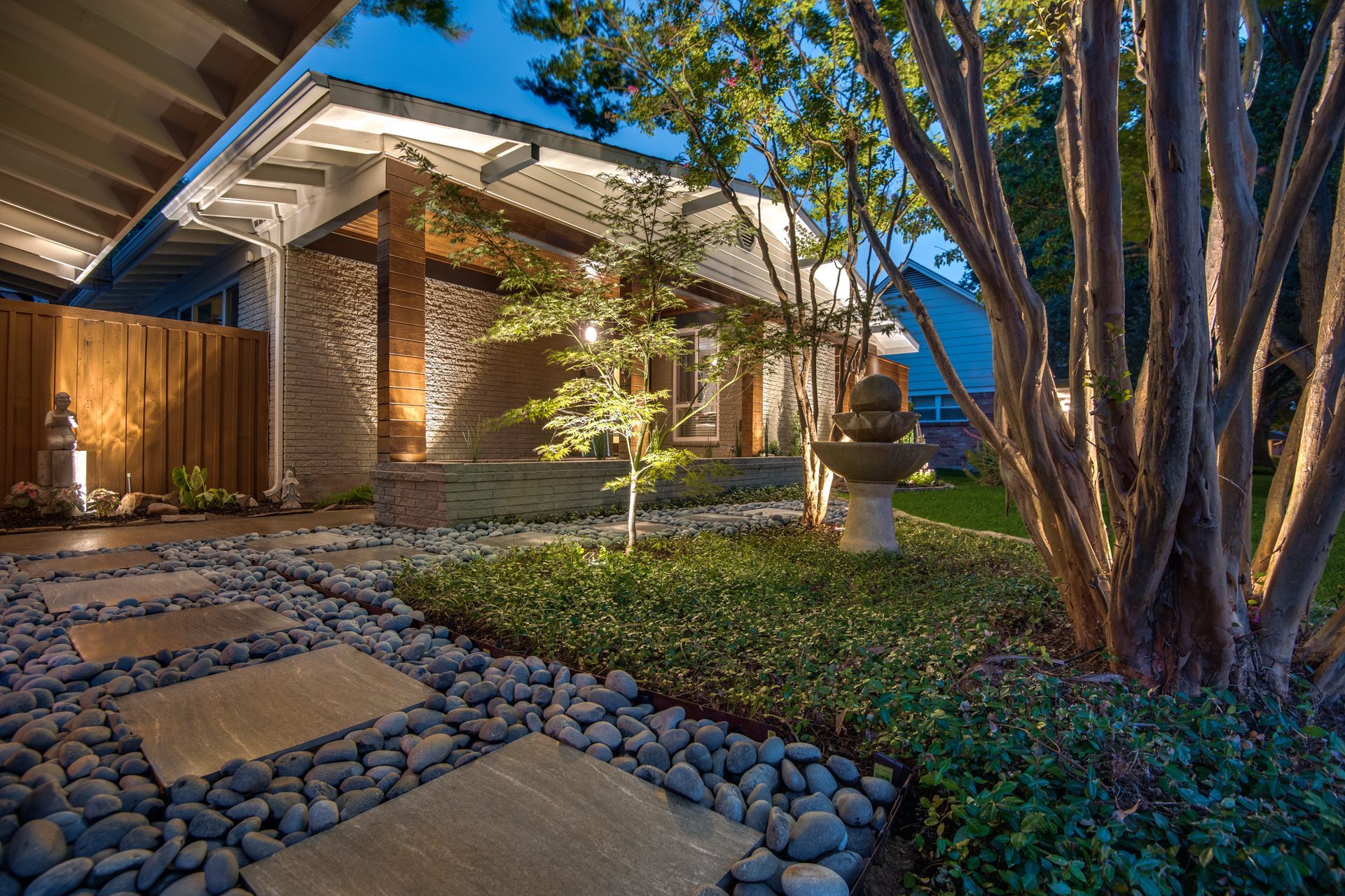 A house with a stone walkway leading to it is lit up at night.