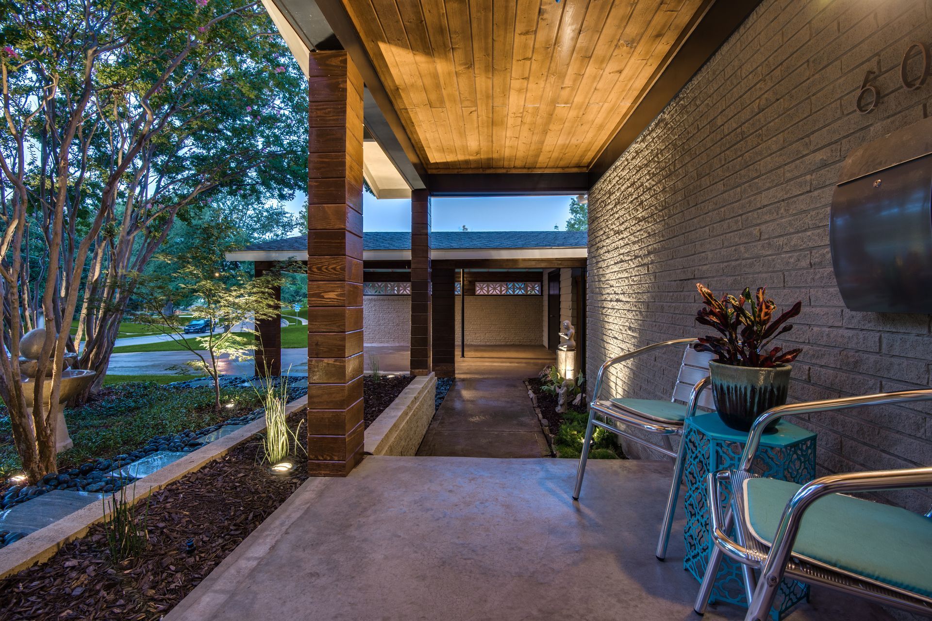 A porch remodel with chairs and a table in front of a brick building.